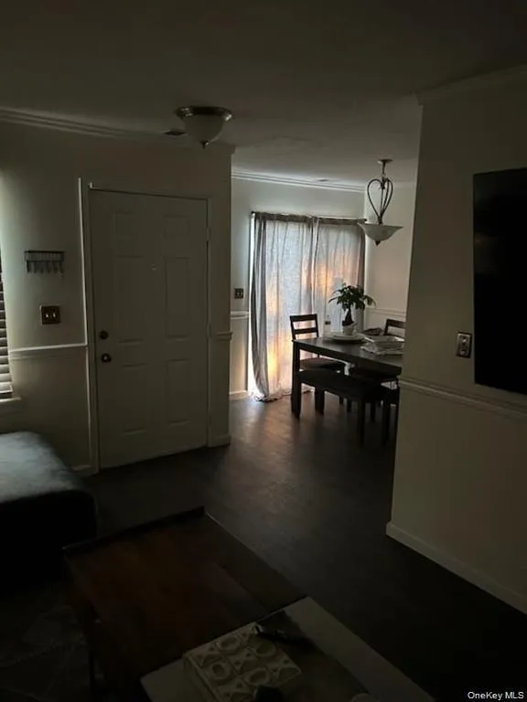 Entrance foyer featuring crown molding and dark wood-style floors Entrance foyer featuring crown molding and dark wood-style floors