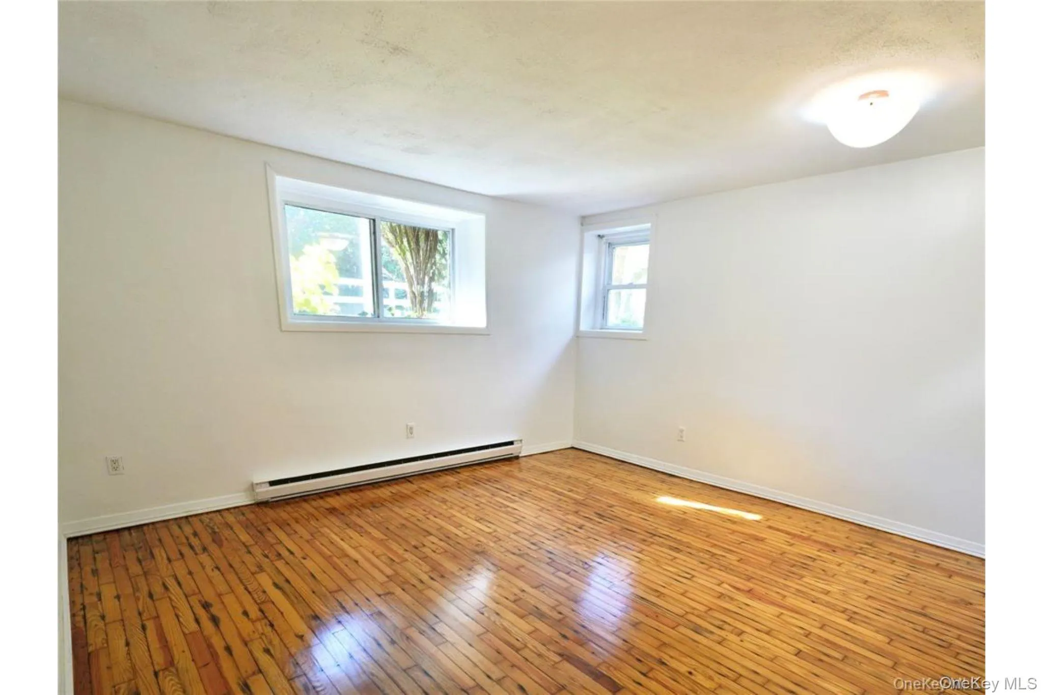 Spare room featuring baseboard heating and light wood-style flooring Spare room featuring baseboard heating and light wood-style flooring