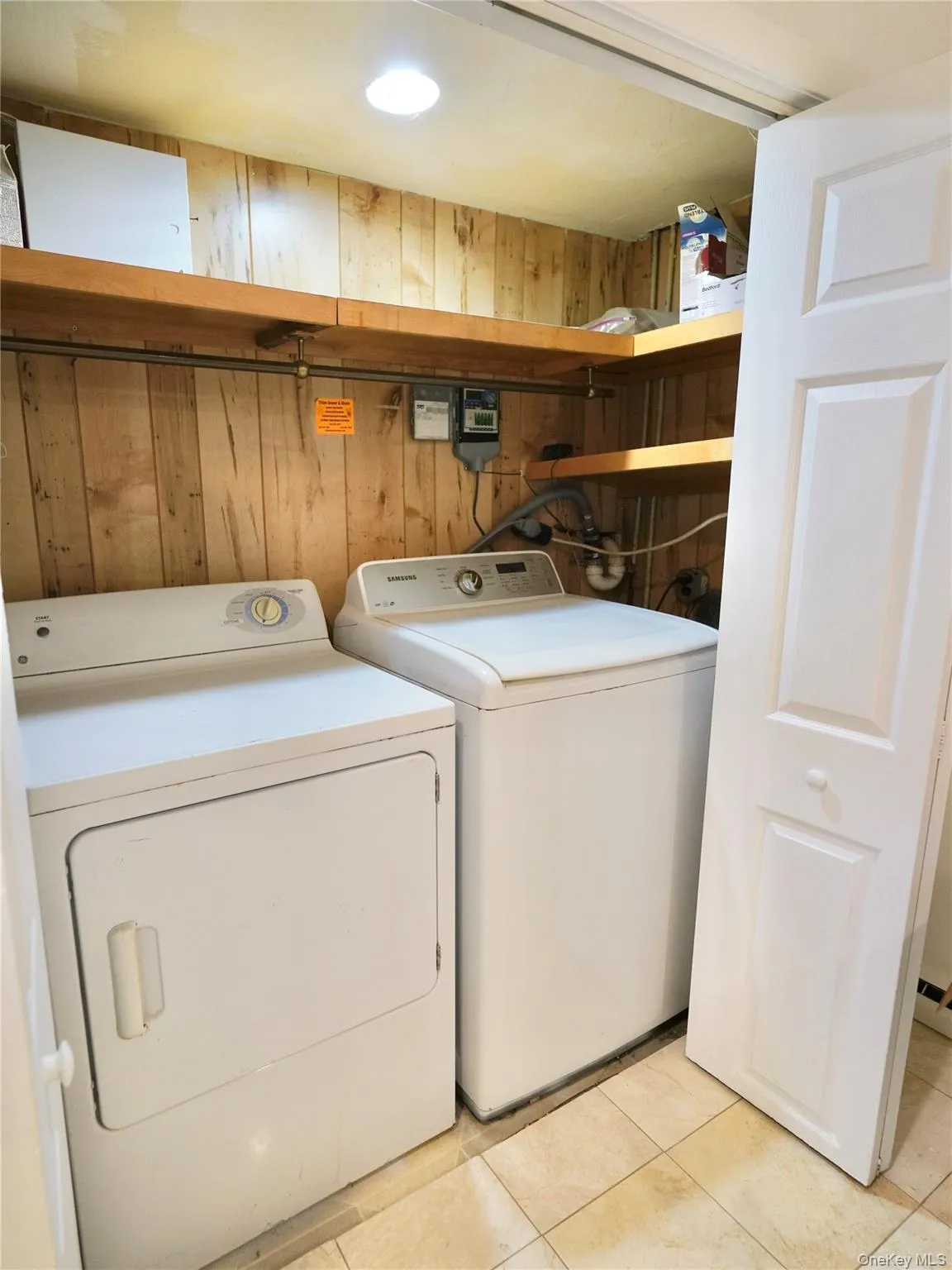 Laundry area featuring wooden walls, light tile patterned floors, and washer and clothes dryer Laundry area featuring wooden walls, light tile patterned floors, and washer and clothes dryer