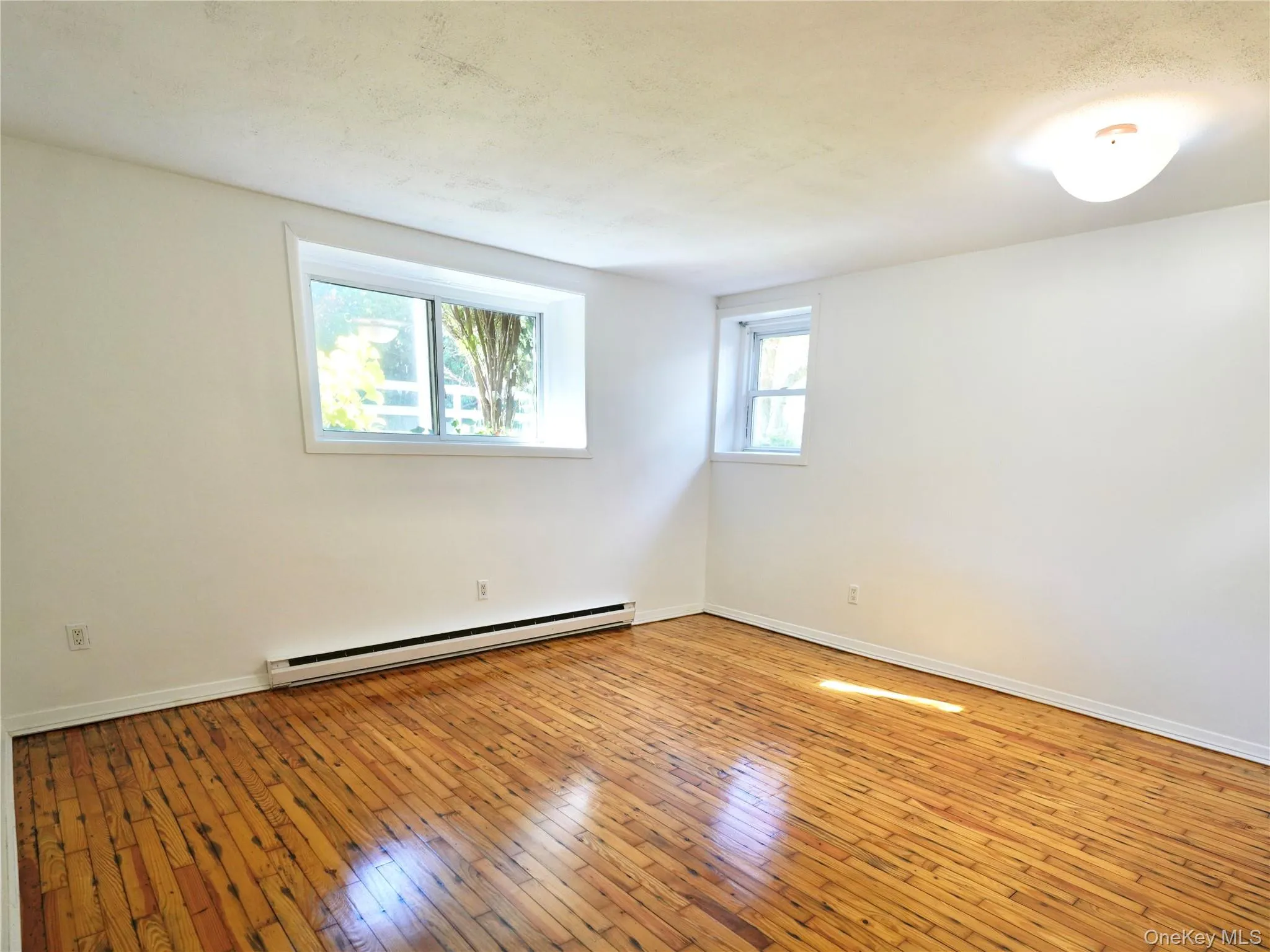 Spare room with light wood finished floors and baseboard heating Spare room with light wood finished floors and baseboard heating