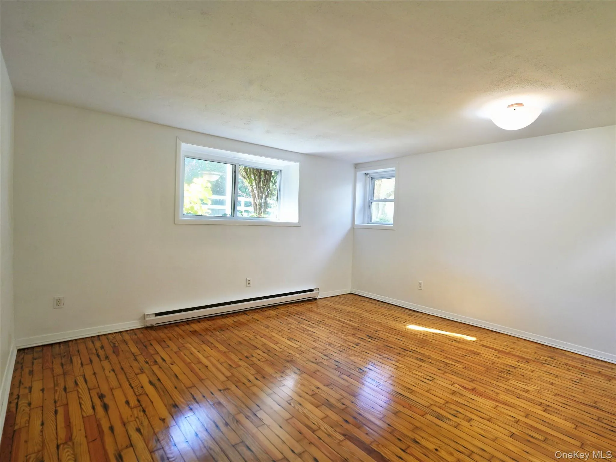 Empty room featuring hardwood / wood-style flooring and a baseboard radiator Empty room featuring hardwood / wood-style flooring and a baseboard radiator