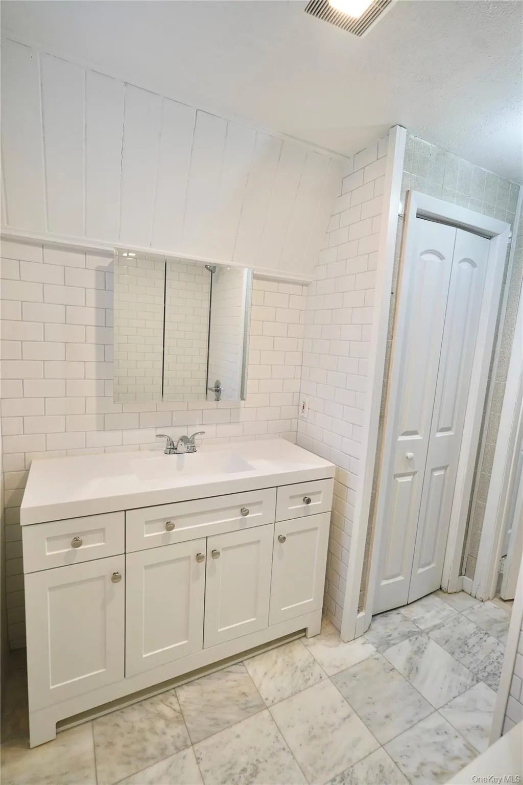 Bathroom featuring tile walls, vanity, a closet, and tasteful backsplash Bathroom featuring tile walls, vanity, a closet, and tasteful backsplash