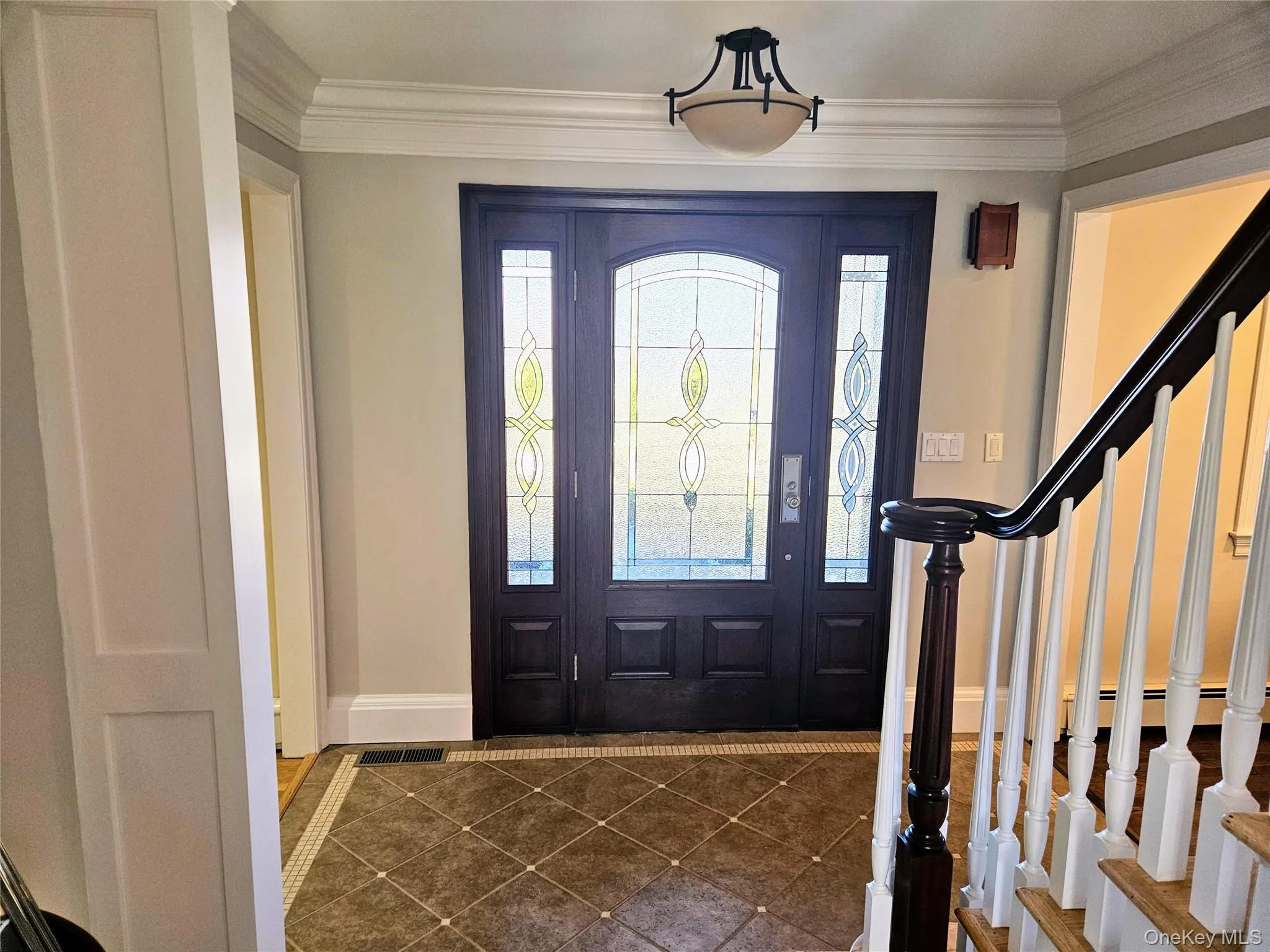 Entrance foyer with crown molding, tile patterned flooring, and stairs Entrance foyer with crown molding, tile patterned flooring, and stairs