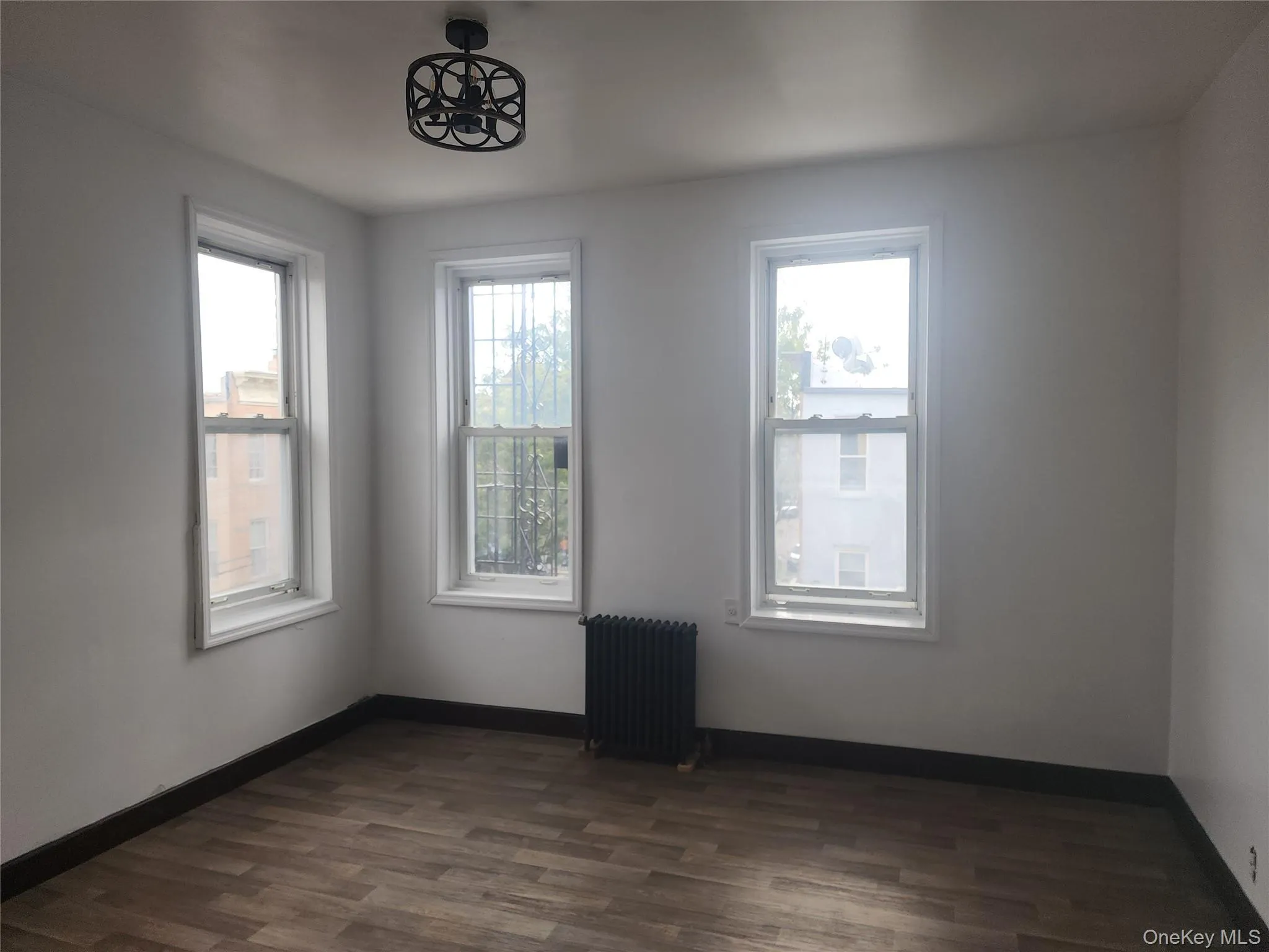 Spare room featuring radiator heating unit and dark wood finished floors Spare room featuring radiator heating unit and dark wood finished floors