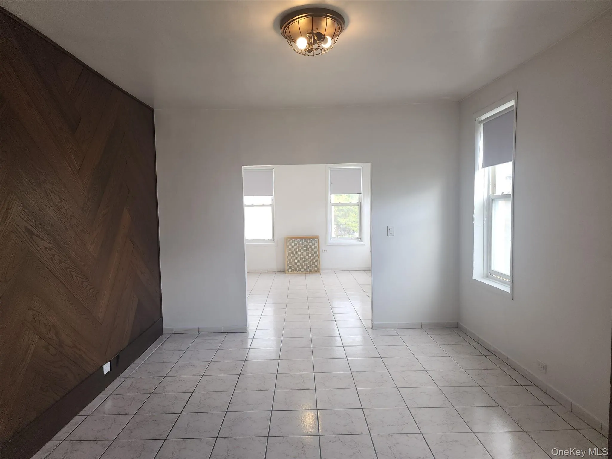 Empty room featuring plenty of natural light, light tile patterned flooring, and wood walls Empty room featuring plenty of natural light, light tile patterned flooring, and wood walls