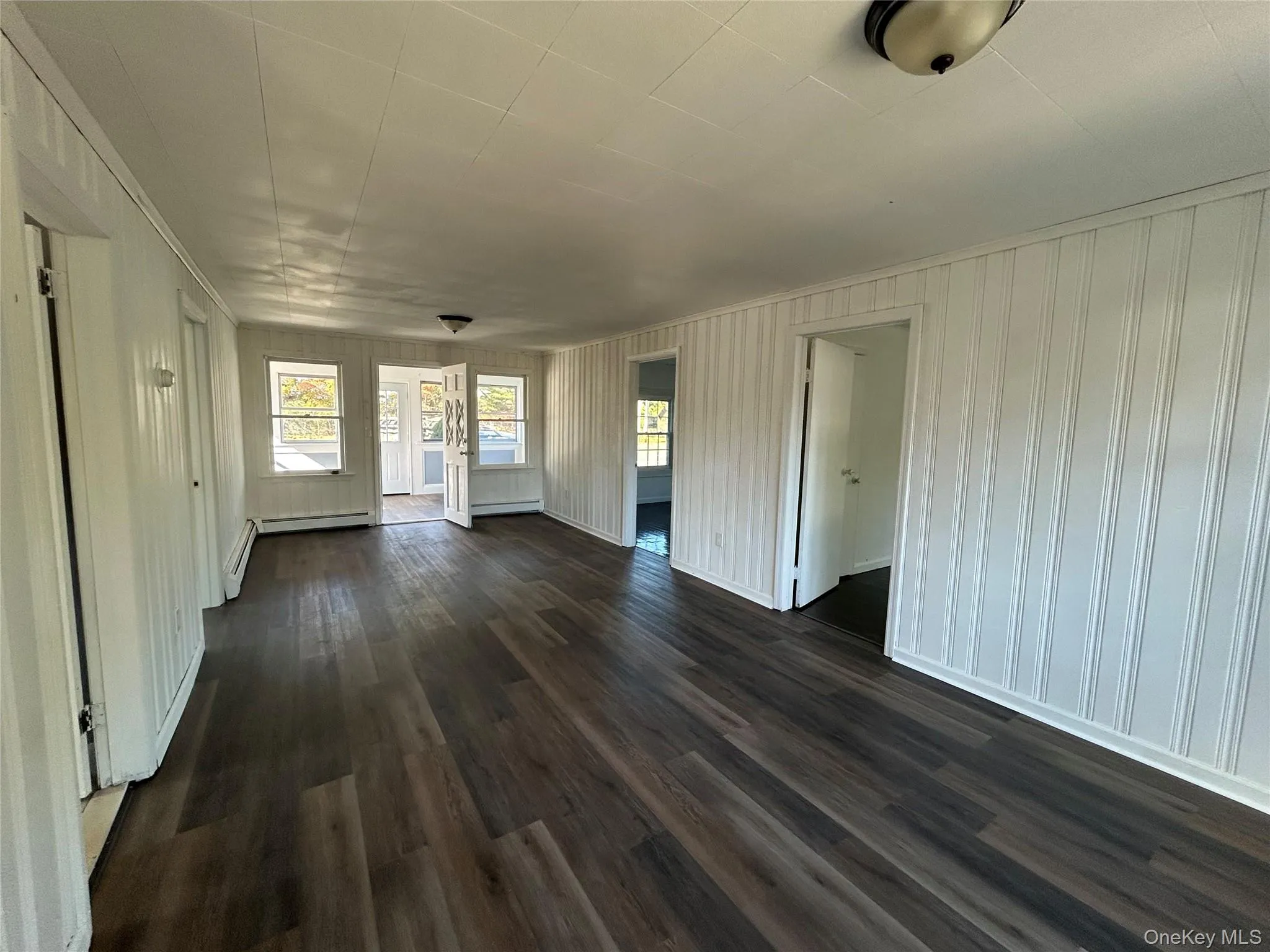 Unfurnished living room with dark wood-type flooring and ornamental molding Unfurnished living room with dark wood-type flooring and ornamental molding