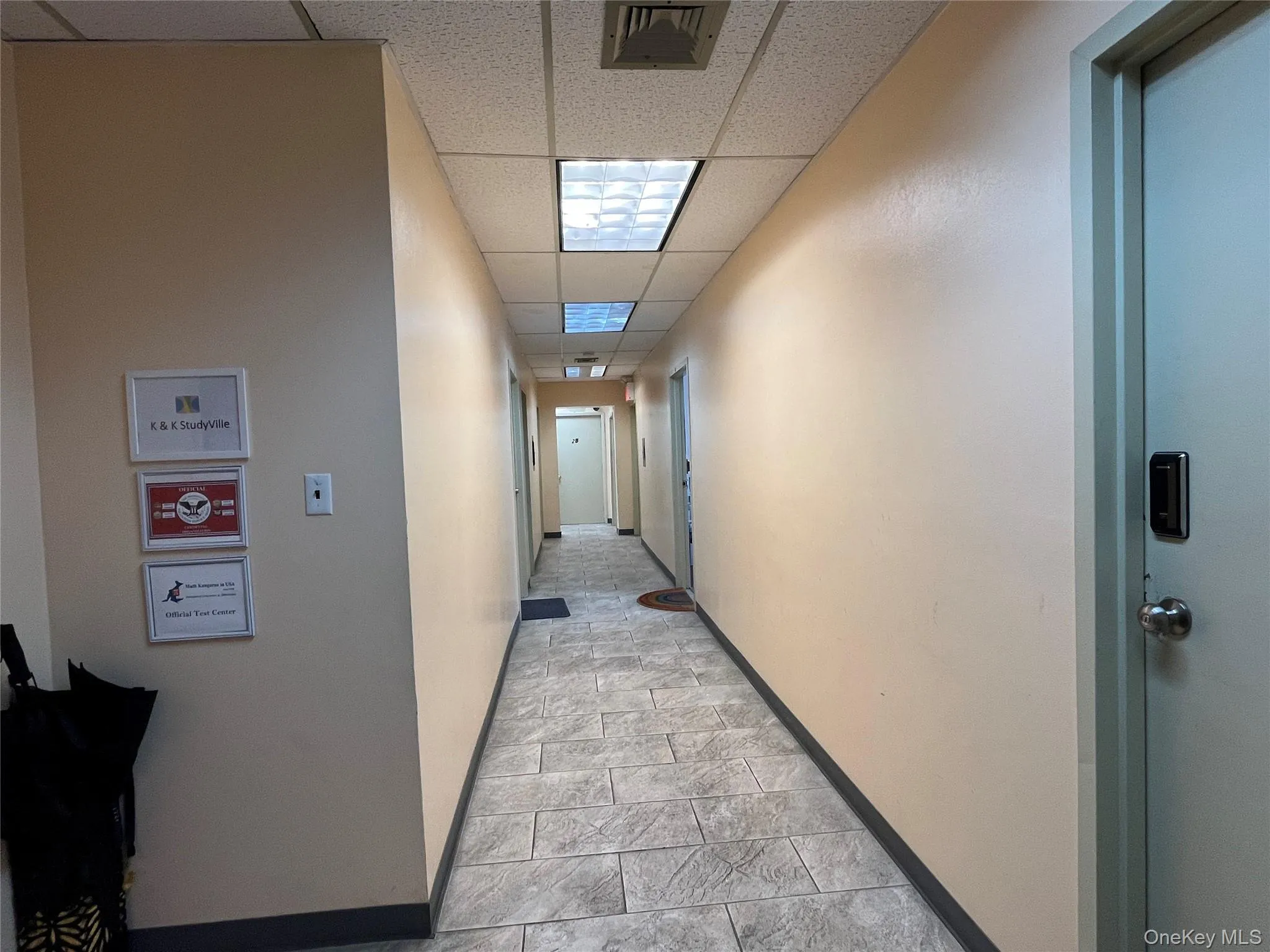 Hallway with a paneled ceiling and baseboards Hallway with a paneled ceiling and baseboards