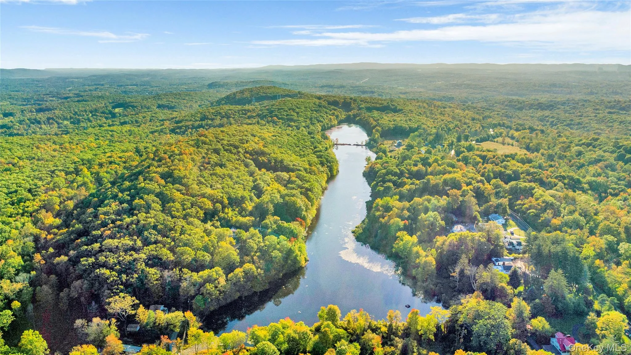 Aerial view of a heavily wooded area and a water and mountain view Aerial view of a heavily wooded area and a water and mountain view