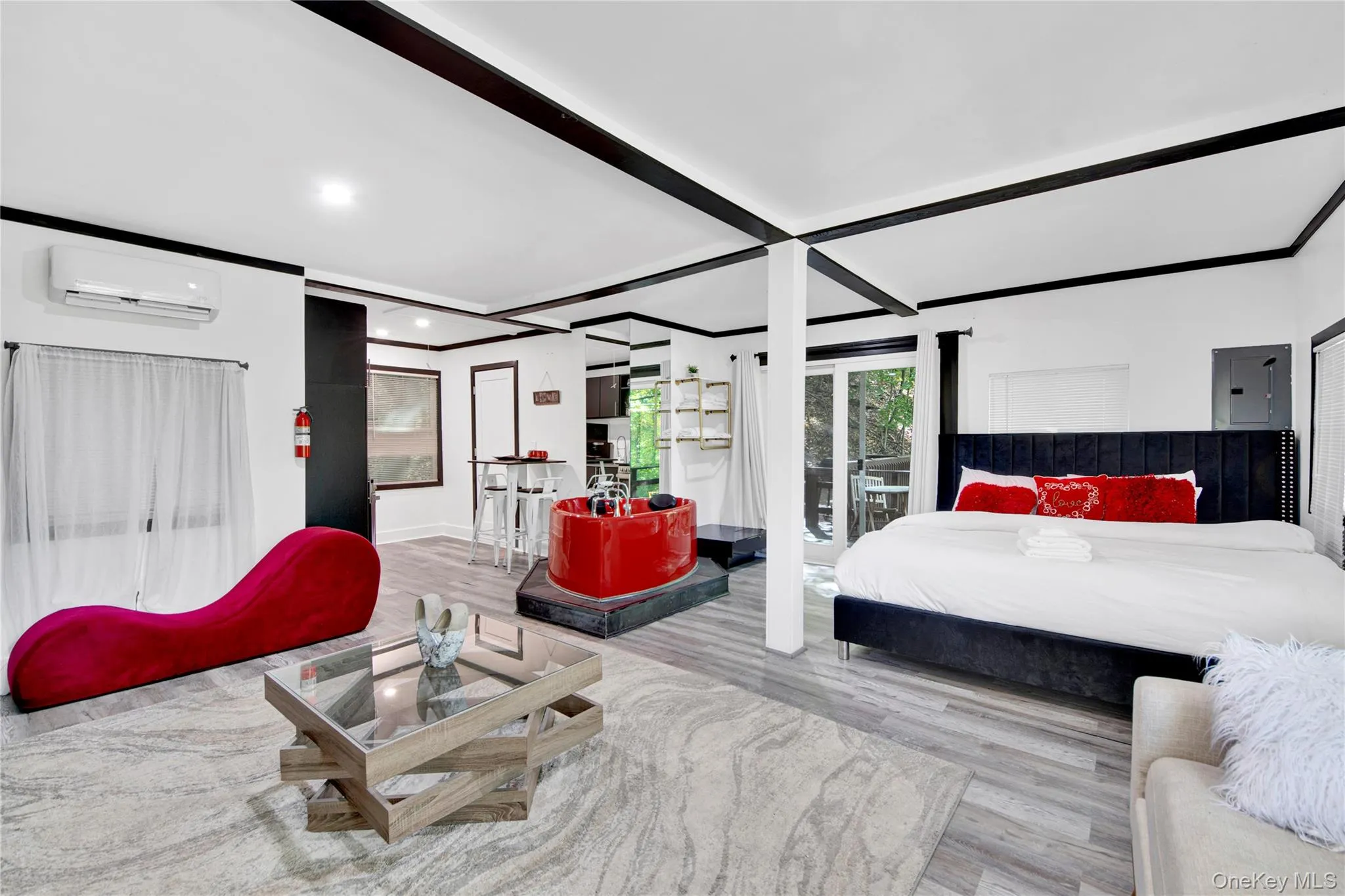 Bedroom with wood finished floors, beamed ceiling, electric panel, recessed lighting, and an AC wall unit Bedroom with wood finished floors, beamed ceiling, electric panel, recessed lighting, and an AC wall unit