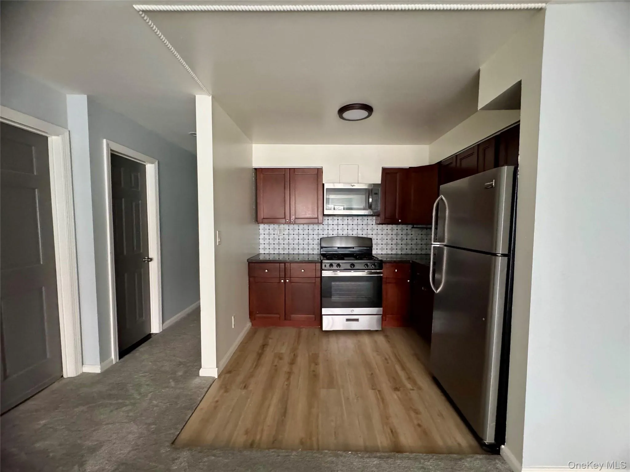 Kitchen featuring stainless steel appliances, decorative backsplash, and light wood-type flooring Kitchen featuring stainless steel appliances, decorative backsplash, and light wood-type flooring