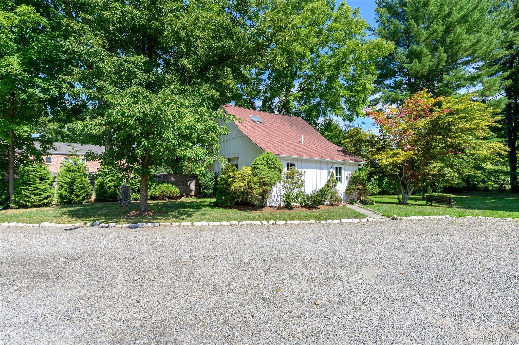 View of front facade with a front yard, a shingled roof, and view of wooded area View of front facade with a front yard, a shingled roof, and view of wooded area