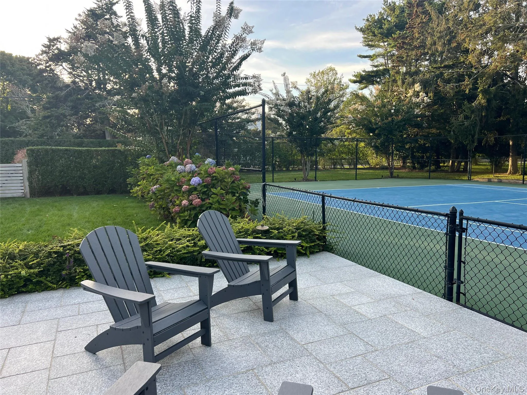 View of tennis court with a patio area View of tennis court with a patio area