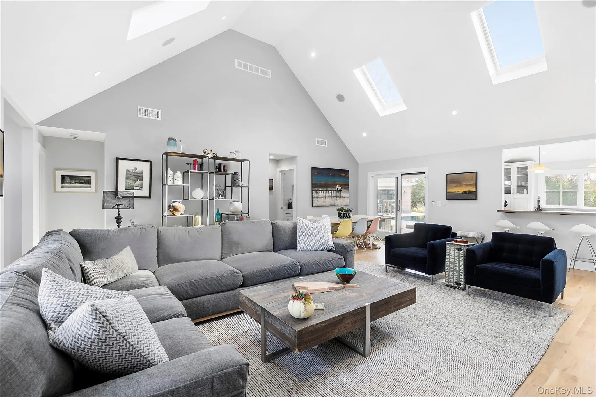 Living room with high vaulted ceiling, wood finished floors, a skylight, and recessed lighting Living room with high vaulted ceiling, wood finished floors, a skylight, and recessed lighting