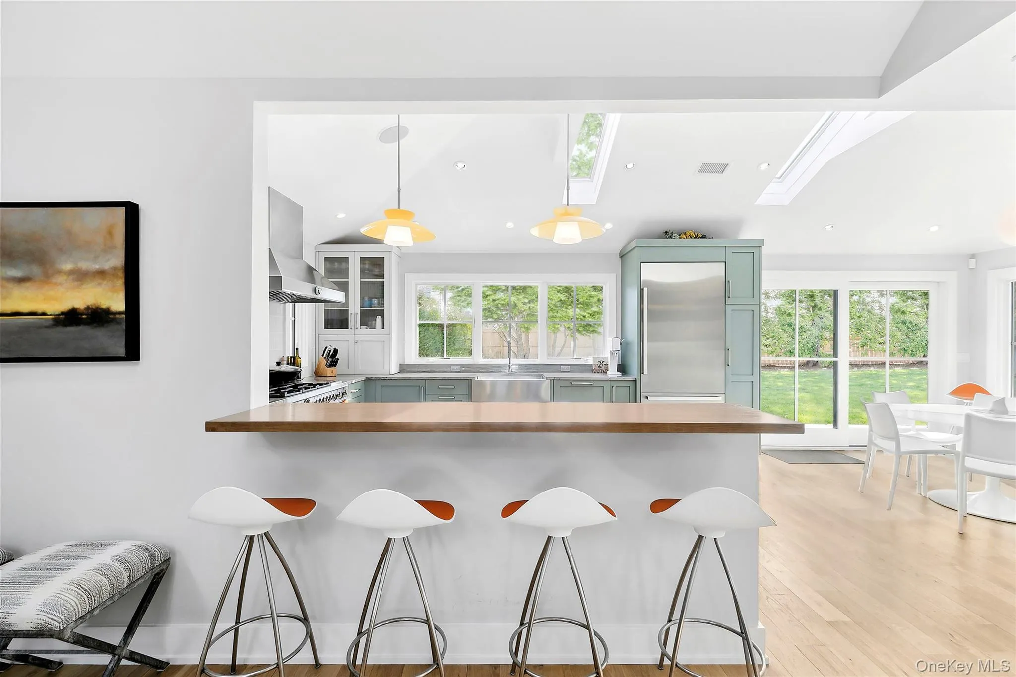 Kitchen with glass insert cabinets, a peninsula, wooden counters, hanging light fixtures, and a kitchen bar Kitchen with glass insert cabinets, a peninsula, wooden counters, hanging light fixtures, and a kitchen bar