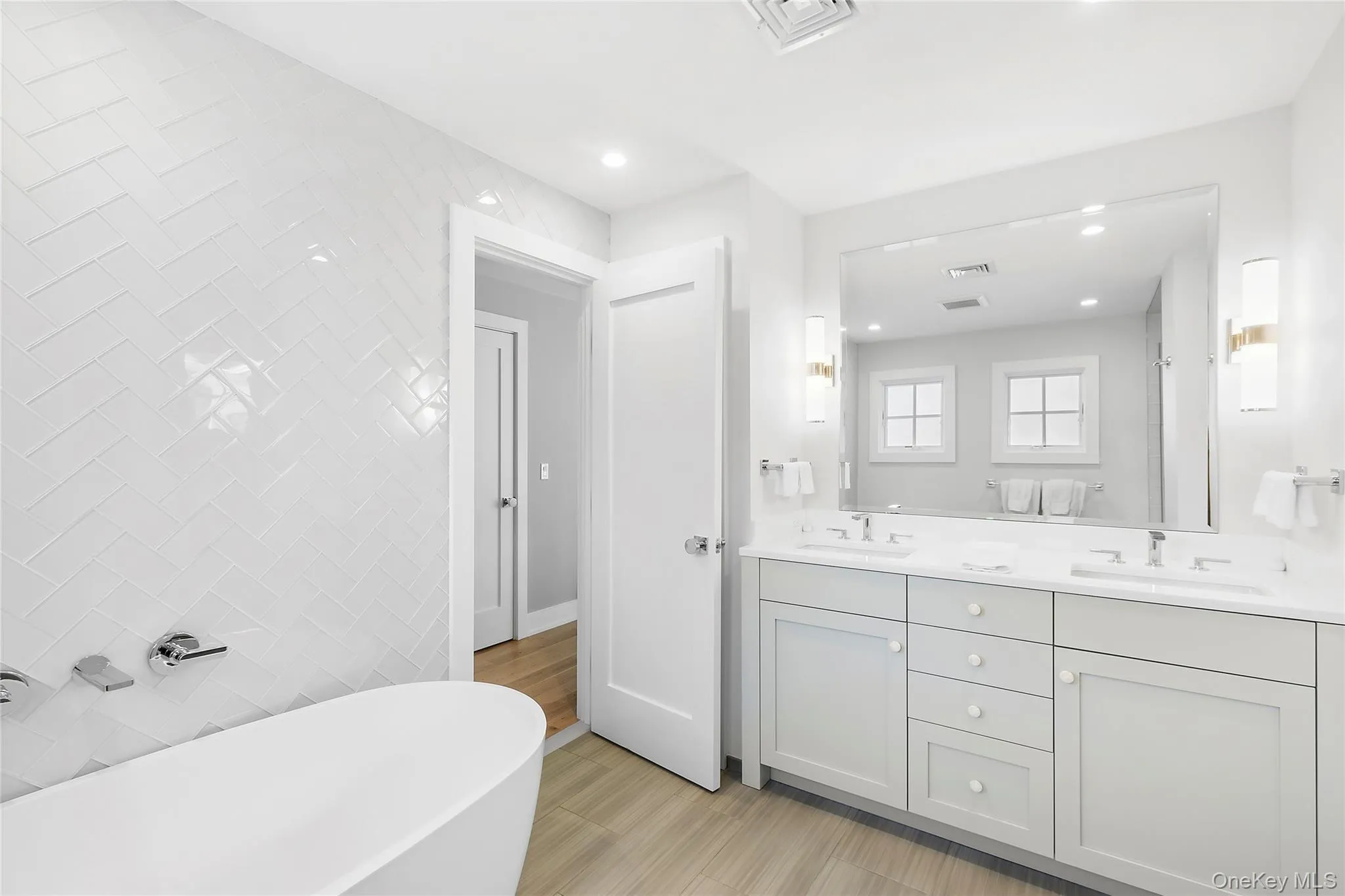 Bathroom featuring a freestanding tub, double vanity, recessed lighting, and light wood-type flooring Bathroom featuring a freestanding tub, double vanity, recessed lighting, and light wood-type flooring