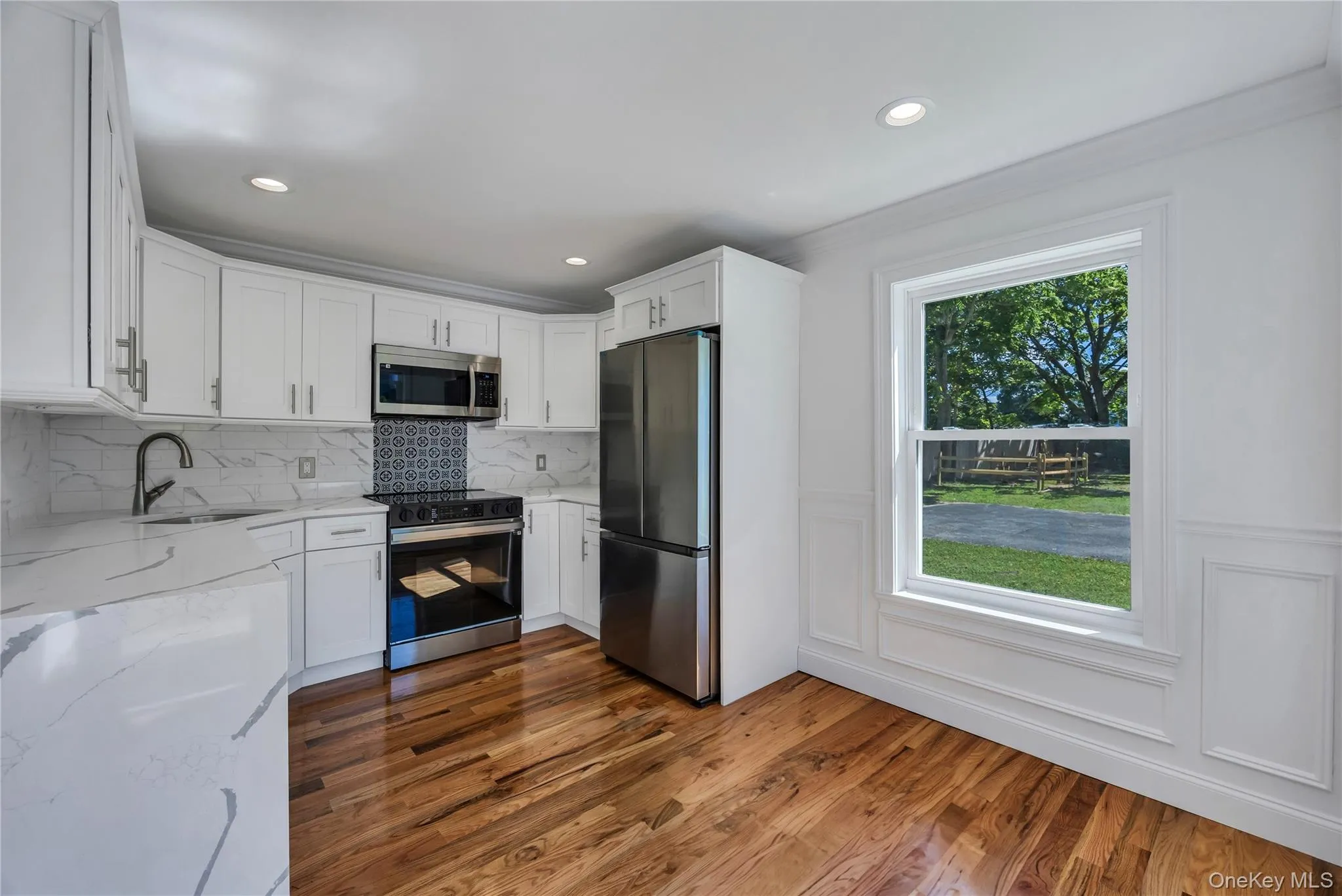 Kitchen featuring light stone counters, appliances with stainless steel finishes, white cabinetry, dark wood-type flooring, and recessed lighting Kitchen featuring light stone counters, appliances with stainless steel finishes, white cabinetry, dark wood-type flooring, and recessed lighting