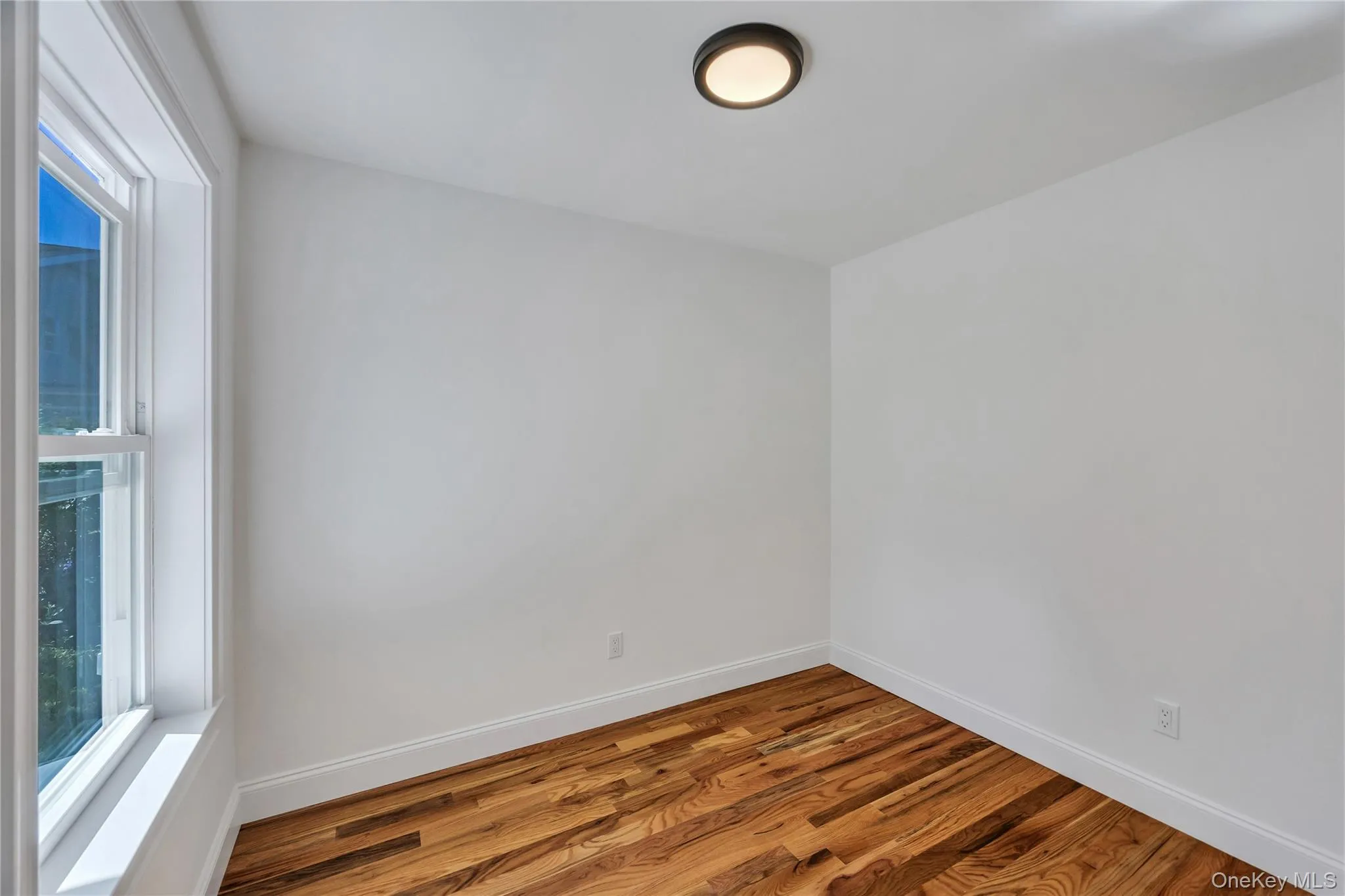 Spare room featuring wood finished floors and baseboards Spare room featuring wood finished floors and baseboards