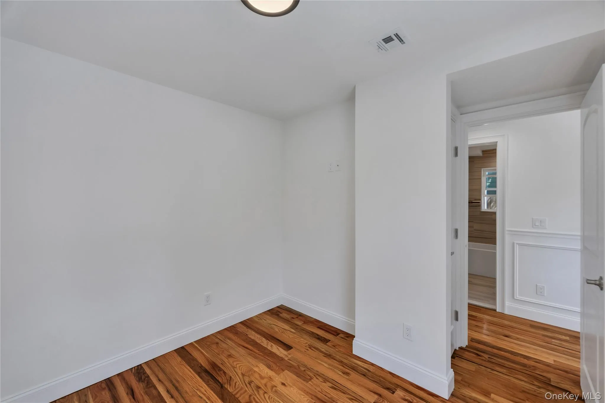 Unfurnished room with wood finished floors and baseboards Unfurnished room with wood finished floors and baseboards