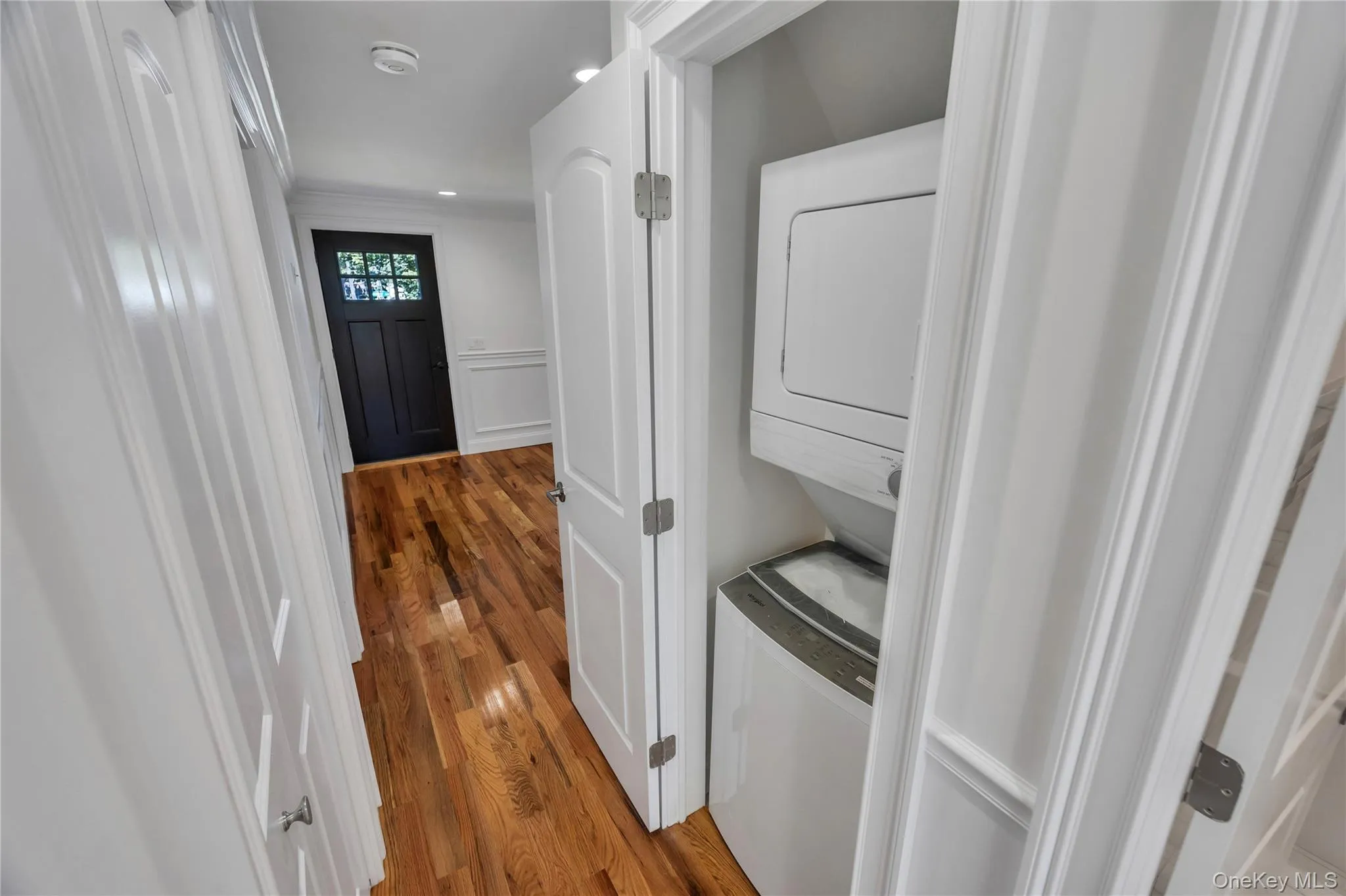 Laundry room with light wood-style flooring and stacked washer / drying machine Laundry room with light wood-style flooring and stacked washer / drying machine