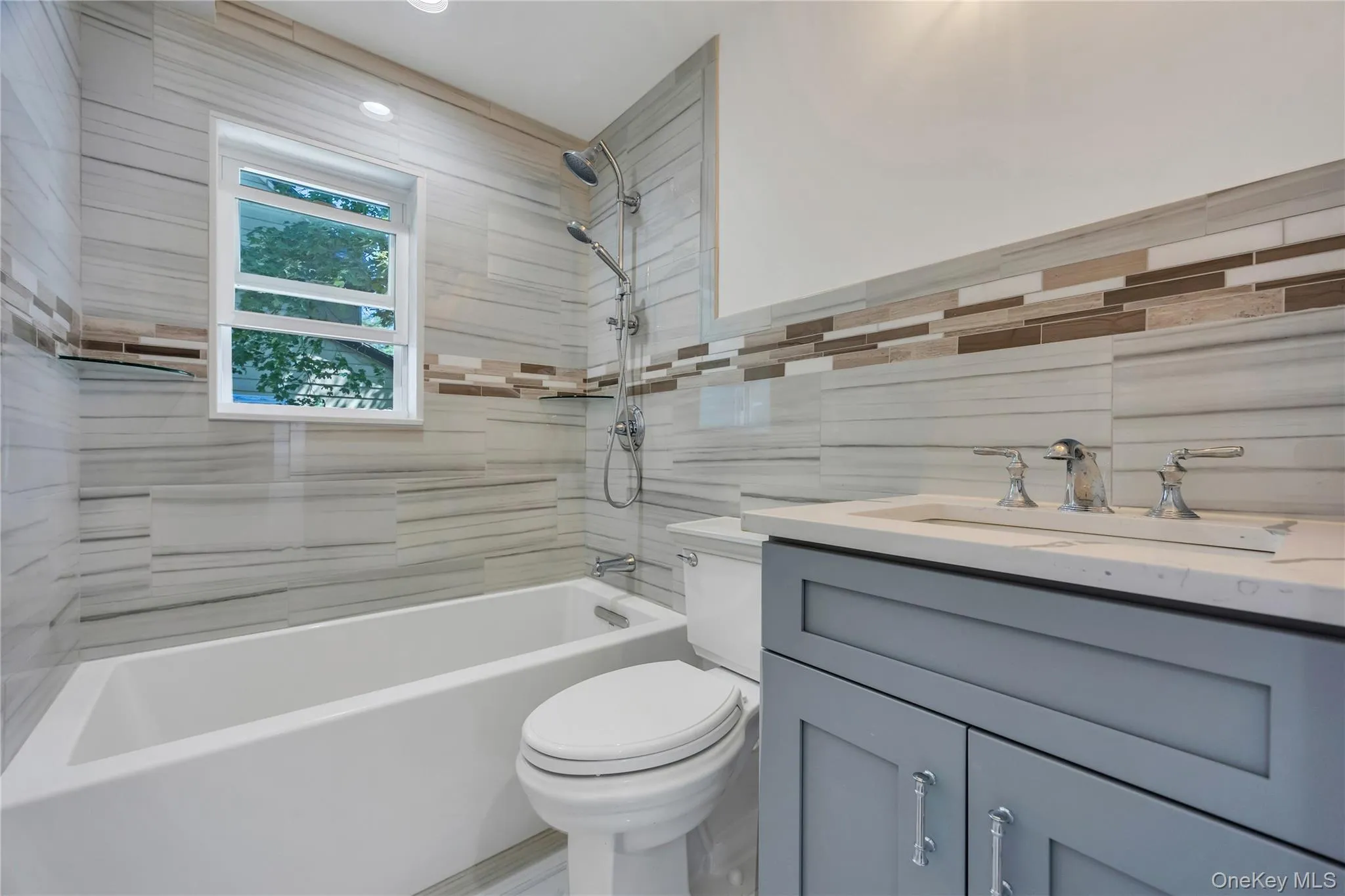 Bathroom with vanity, shower / tub combination, and tile walls Bathroom with vanity, shower / tub combination, and tile walls