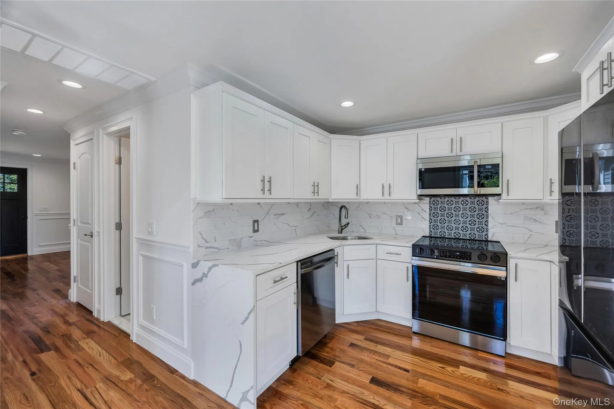 Kitchen featuring appliances with stainless steel finishes, light stone counters, backsplash, white cabinets, and recessed lighting Kitchen featuring appliances with stainless steel finishes, light stone counters, backsplash, white cabinets, and recessed lighting