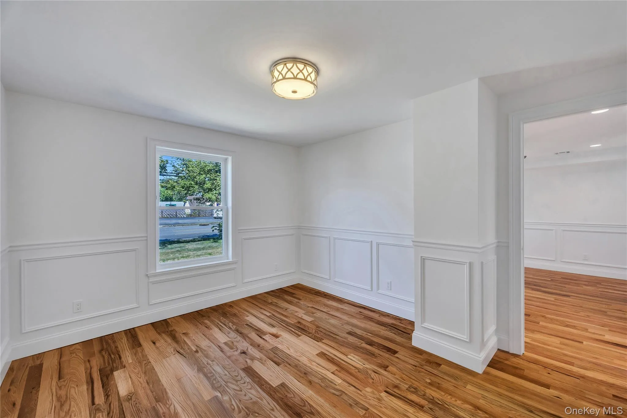Unfurnished room with a decorative wall, wainscoting, and light wood-style flooring Unfurnished room with a decorative wall, wainscoting, and light wood-style flooring