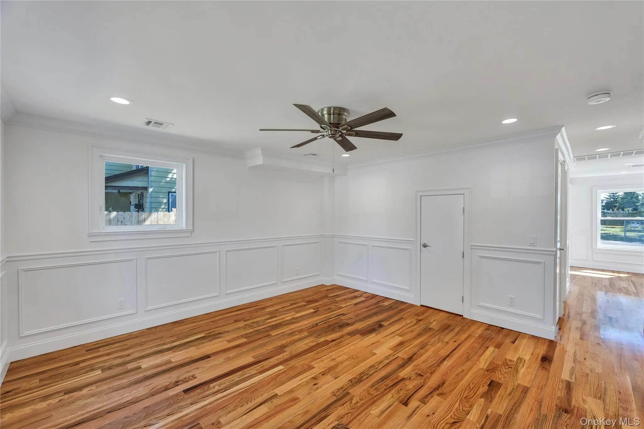 Empty room with a decorative wall, light wood-type flooring, ornamental molding, wainscoting, and recessed lighting Empty room with a decorative wall, light wood-type flooring, ornamental molding, wainscoting, and recessed lighting