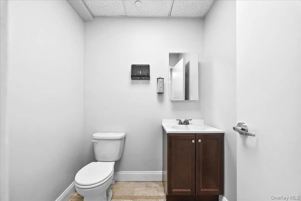 Bathroom with a drop ceiling, vanity, and light tile patterned floors Bathroom with a drop ceiling, vanity, and light tile patterned floors