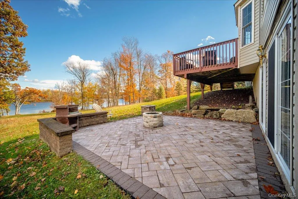 View of patio / terrace featuring an outdoor fire pit and a deck with water view View of patio / terrace featuring an outdoor fire pit and a deck with water view