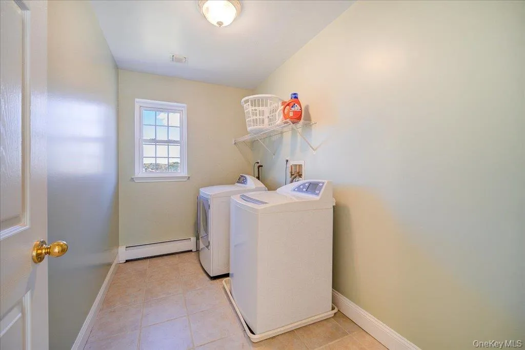 Laundry room featuring light tile patterned floors, a baseboard radiator, and independent washer and dryer Laundry room featuring light tile patterned floors, a baseboard radiator, and independent washer and dryer