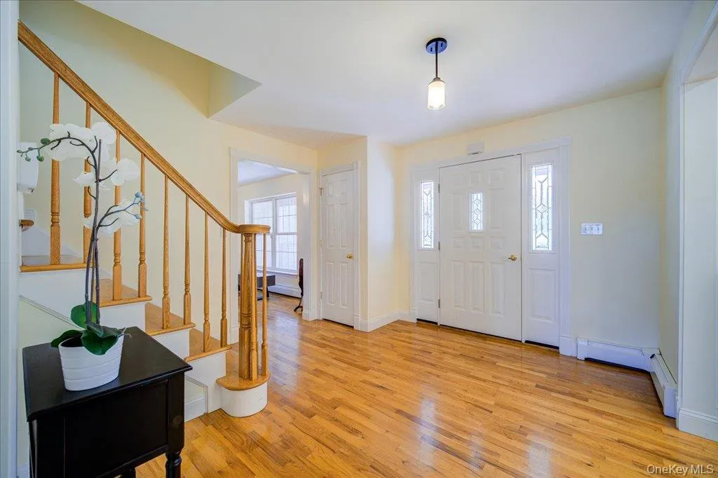 Entrance foyer featuring light wood flooring, stairs, and baseboard heating Entrance foyer featuring light wood flooring, stairs, and baseboard heating