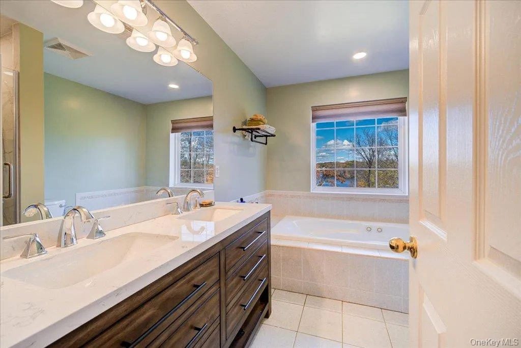 Full bathroom with double vanity, a garden tub, light tile patterned floors, and recessed lighting Full bathroom with double vanity, a garden tub, light tile patterned floors, and recessed lighting