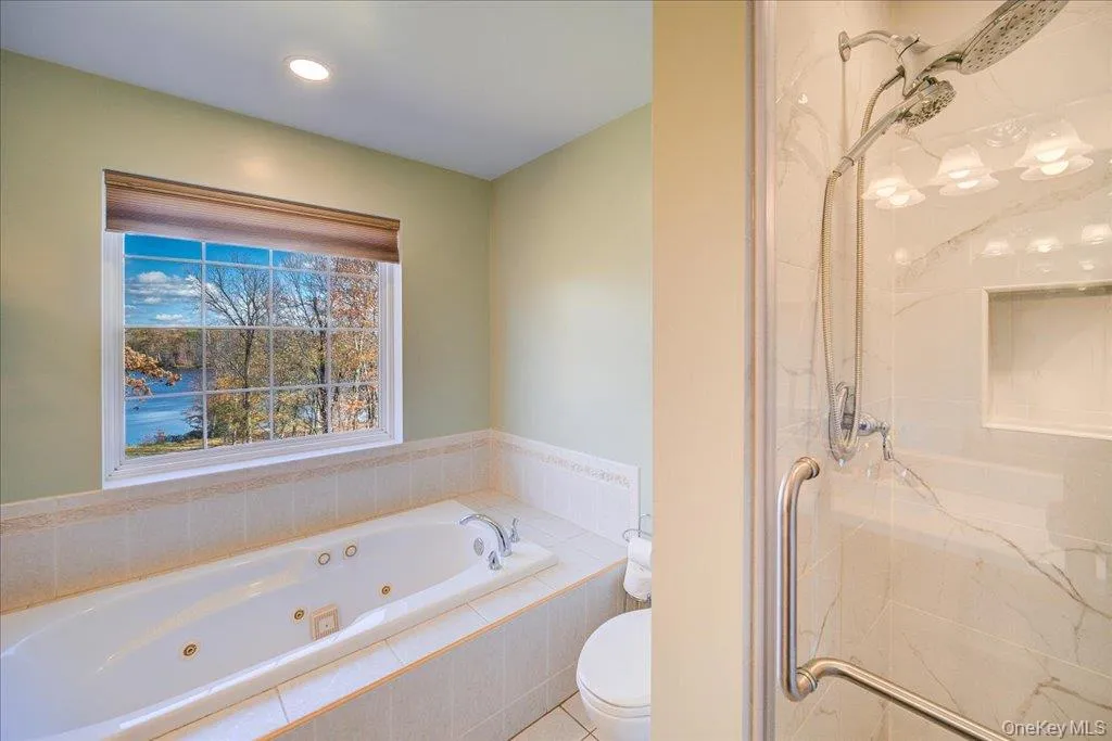 Full bathroom featuring a marble finish shower, a whirlpool tub, recessed lighting, and light tile patterned flooring Full bathroom featuring a marble finish shower, a whirlpool tub, recessed lighting, and light tile patterned flooring