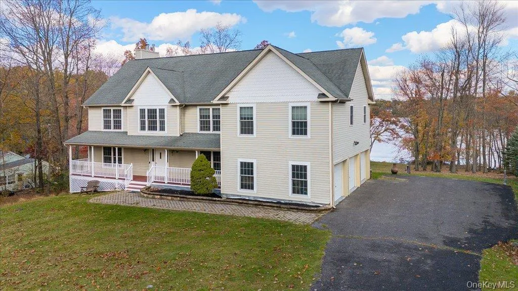 View of front facade featuring a porch, asphalt driveway, a front lawn, a chimney, and roof with shingles on Lake View of front facade featuring a porch, asphalt driveway, a front lawn, a chimney, and roof with shingles on Lake