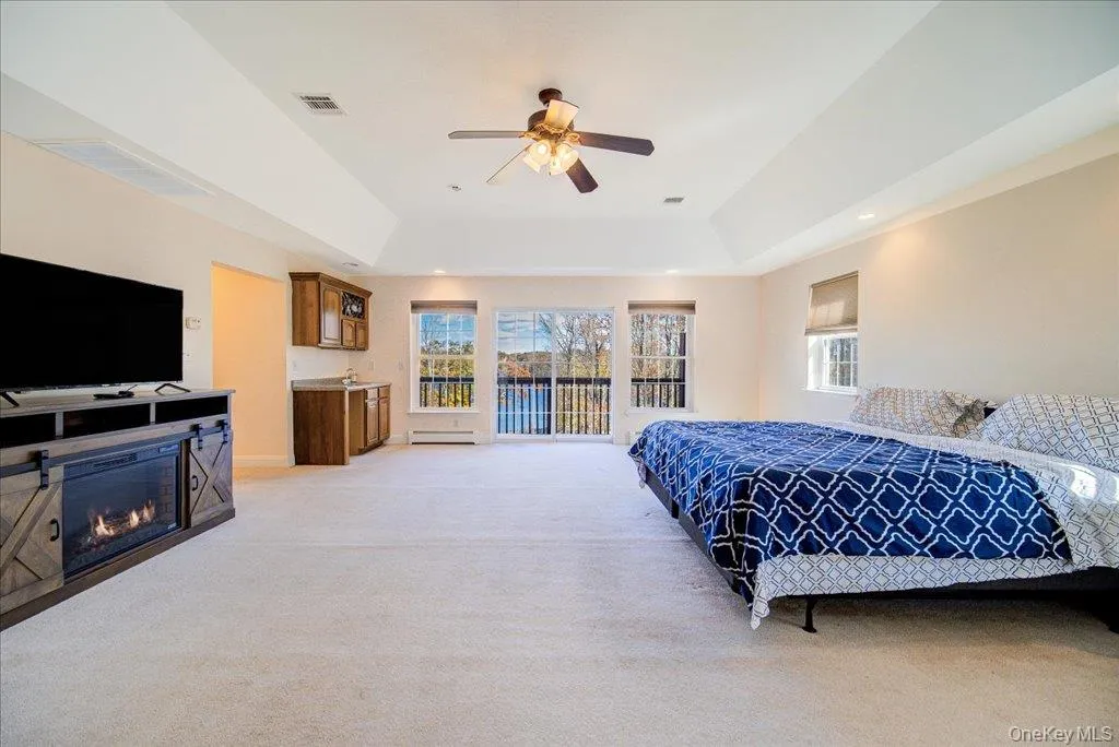 Bedroom with a tray ceiling, light carpet, access to juliette balcony Bedroom with a tray ceiling, light carpet, access to juliette balcony