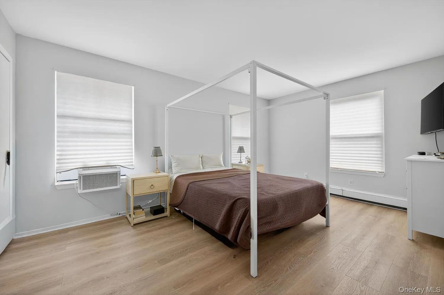Bedroom with light wood-style floors and a baseboard radiator Bedroom with light wood-style floors and a baseboard radiator