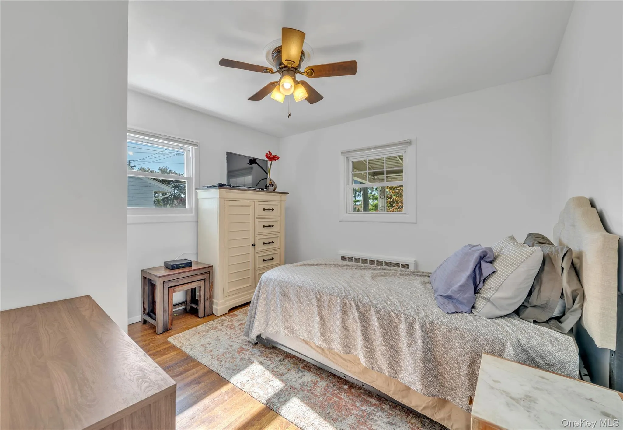 Bedroom with light wood finished floors, multiple windows, and ceiling fan Bedroom with light wood finished floors, multiple windows, and ceiling fan