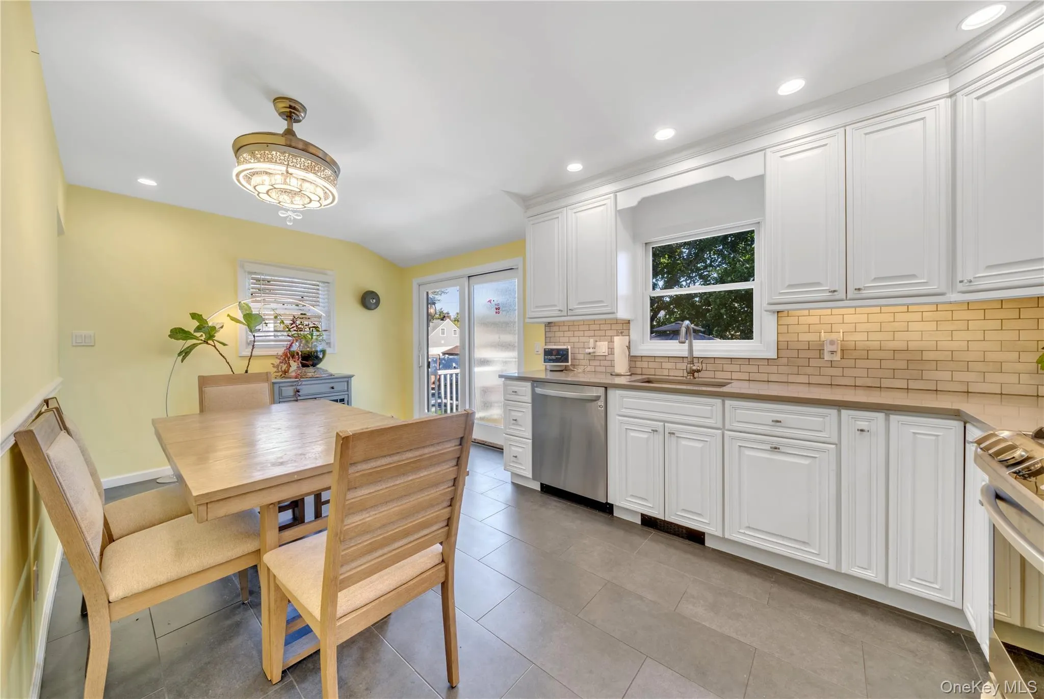 Kitchen with tasteful backsplash, white cabinets, recessed lighting, appliances with stainless steel finishes, and light tile patterned flooring Kitchen with tasteful backsplash, white cabinets, recessed lighting, appliances with stainless steel finishes, and light tile patterned flooring