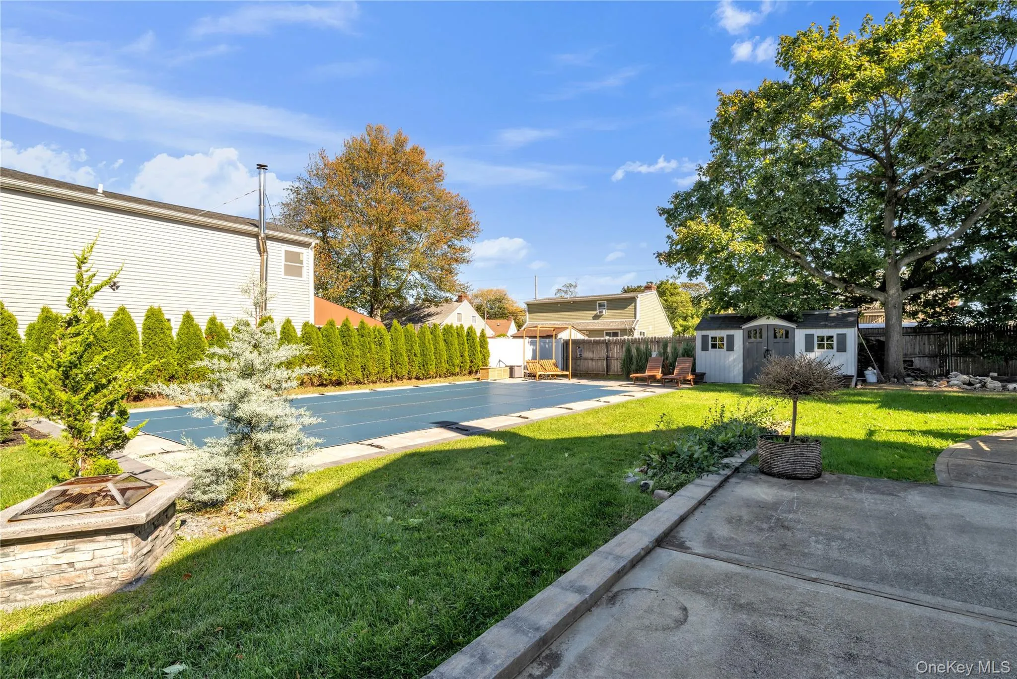 Fenced backyard with a fire pit, a patio area, and a storage unit Fenced backyard with a fire pit, a patio area, and a storage unit