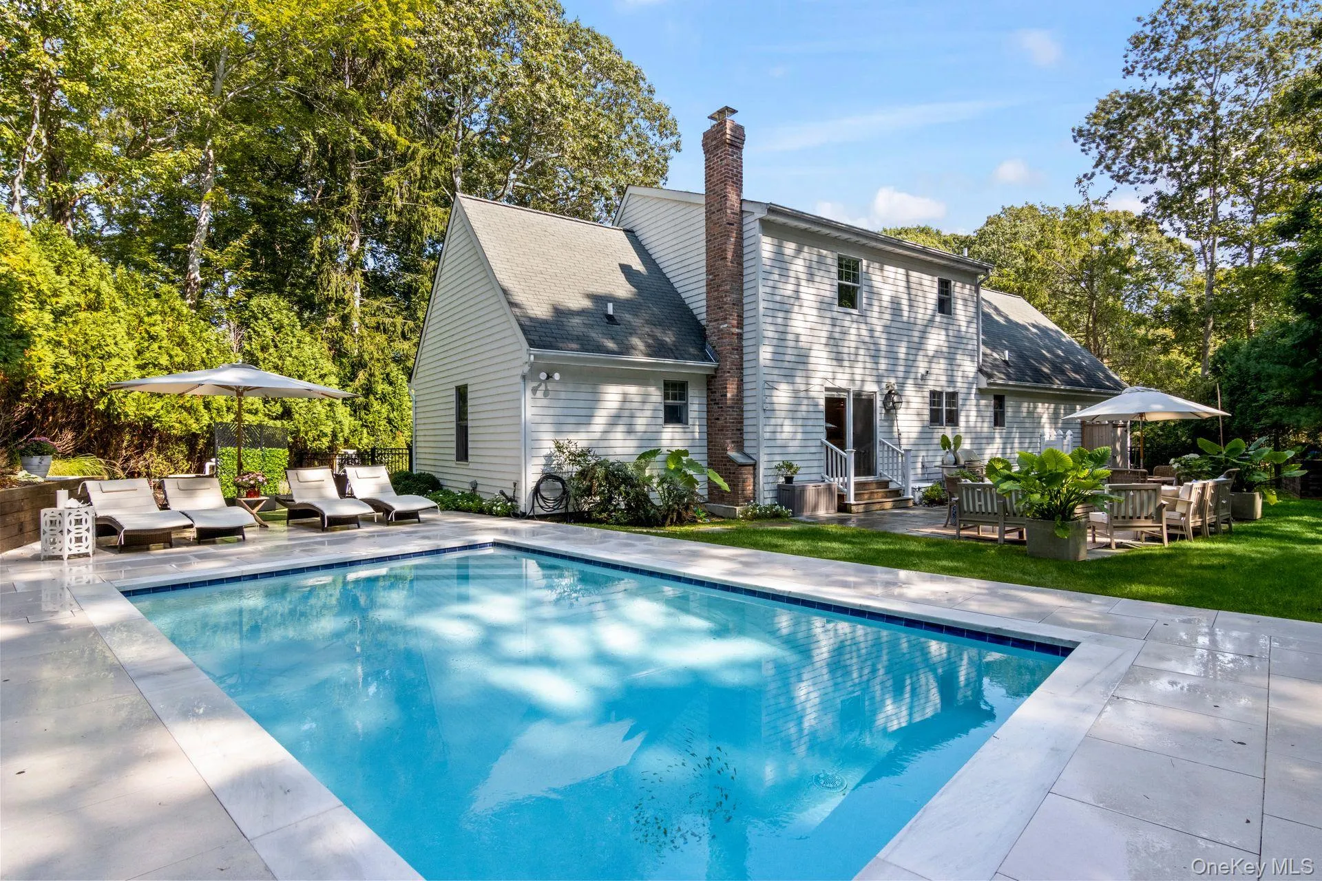 Rear view of house featuring a patio, a chimney, an outdoor pool, and an outdoor living space Rear view of house featuring a patio, a chimney, an outdoor pool, and an outdoor living space