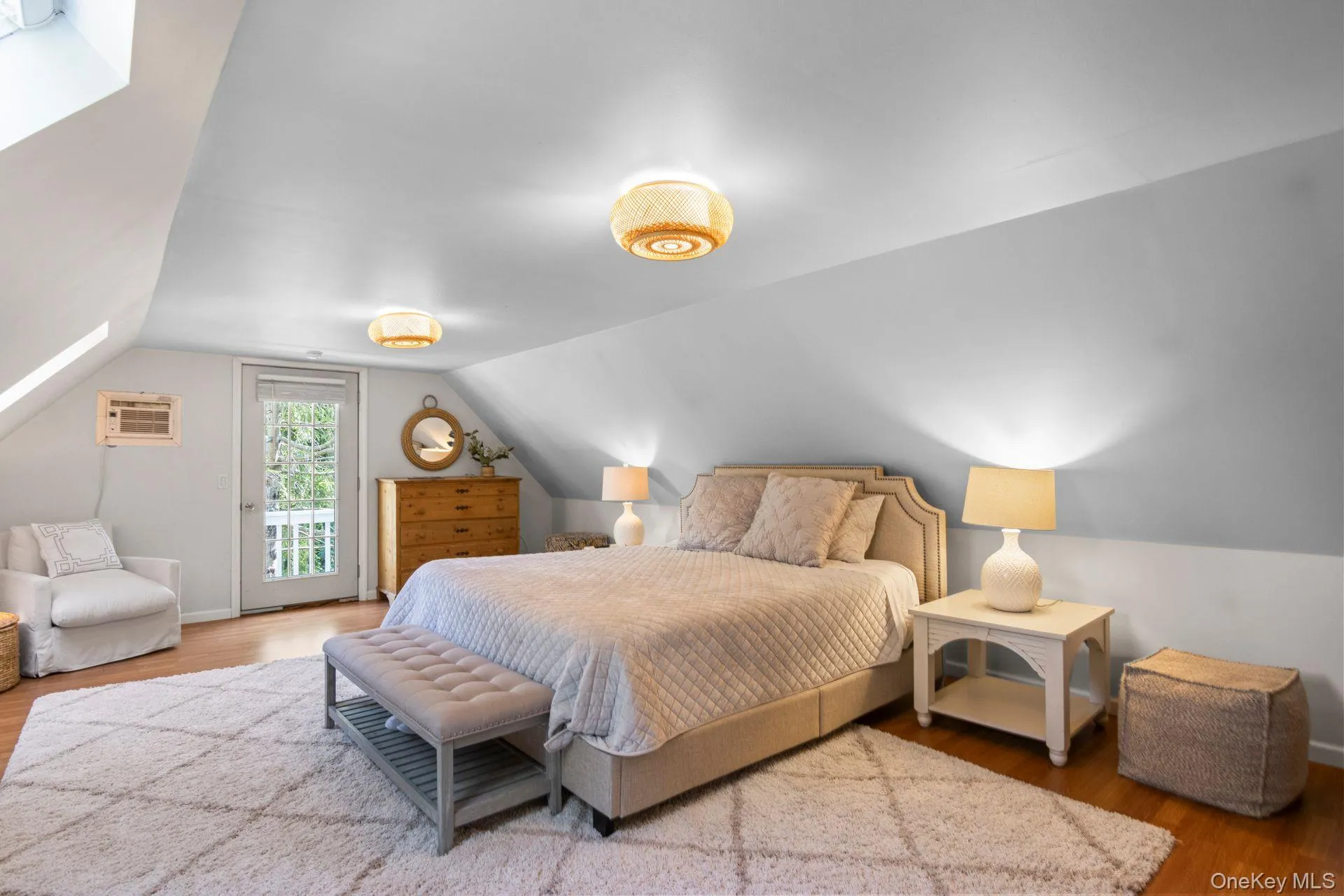 Bedroom featuring wood finished floors, vaulted ceiling, access to exterior, and a wall mounted AC Bedroom featuring wood finished floors, vaulted ceiling, access to exterior, and a wall mounted AC