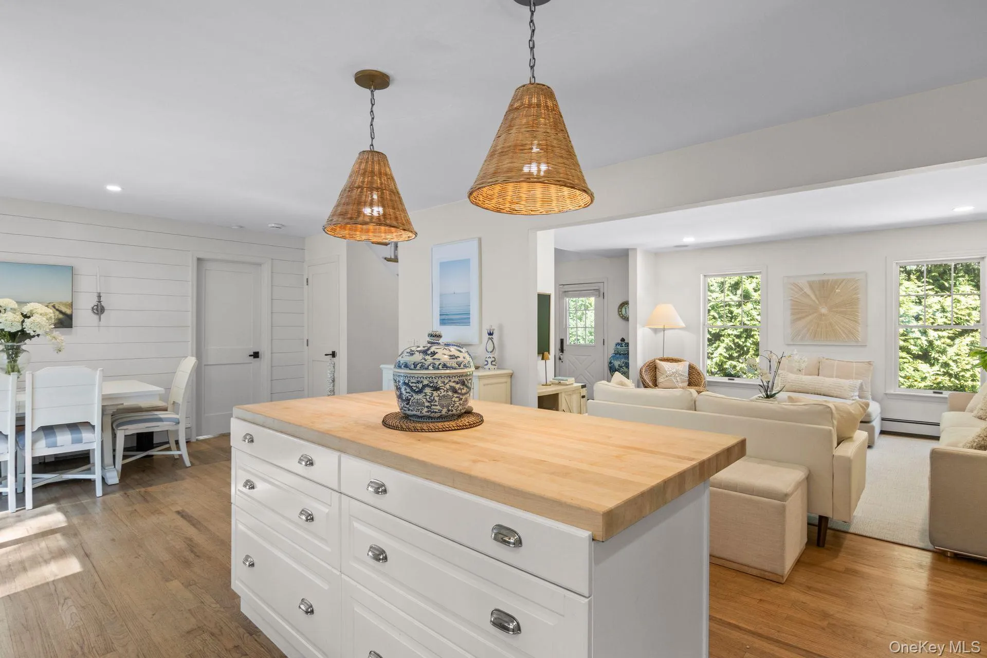 Kitchen featuring butcher block countertops, white cabinetry, pendant lighting, light wood-style floors, and a center island Kitchen featuring butcher block countertops, white cabinetry, pendant lighting, light wood-style floors, and a center island