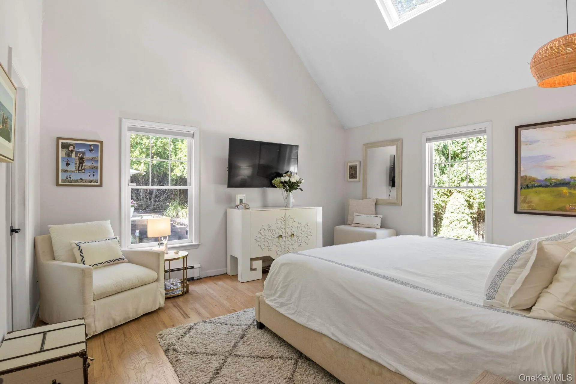 Bedroom featuring a skylight, high vaulted ceiling, light wood finished floors, and baseboard heating Bedroom featuring a skylight, high vaulted ceiling, light wood finished floors, and baseboard heating