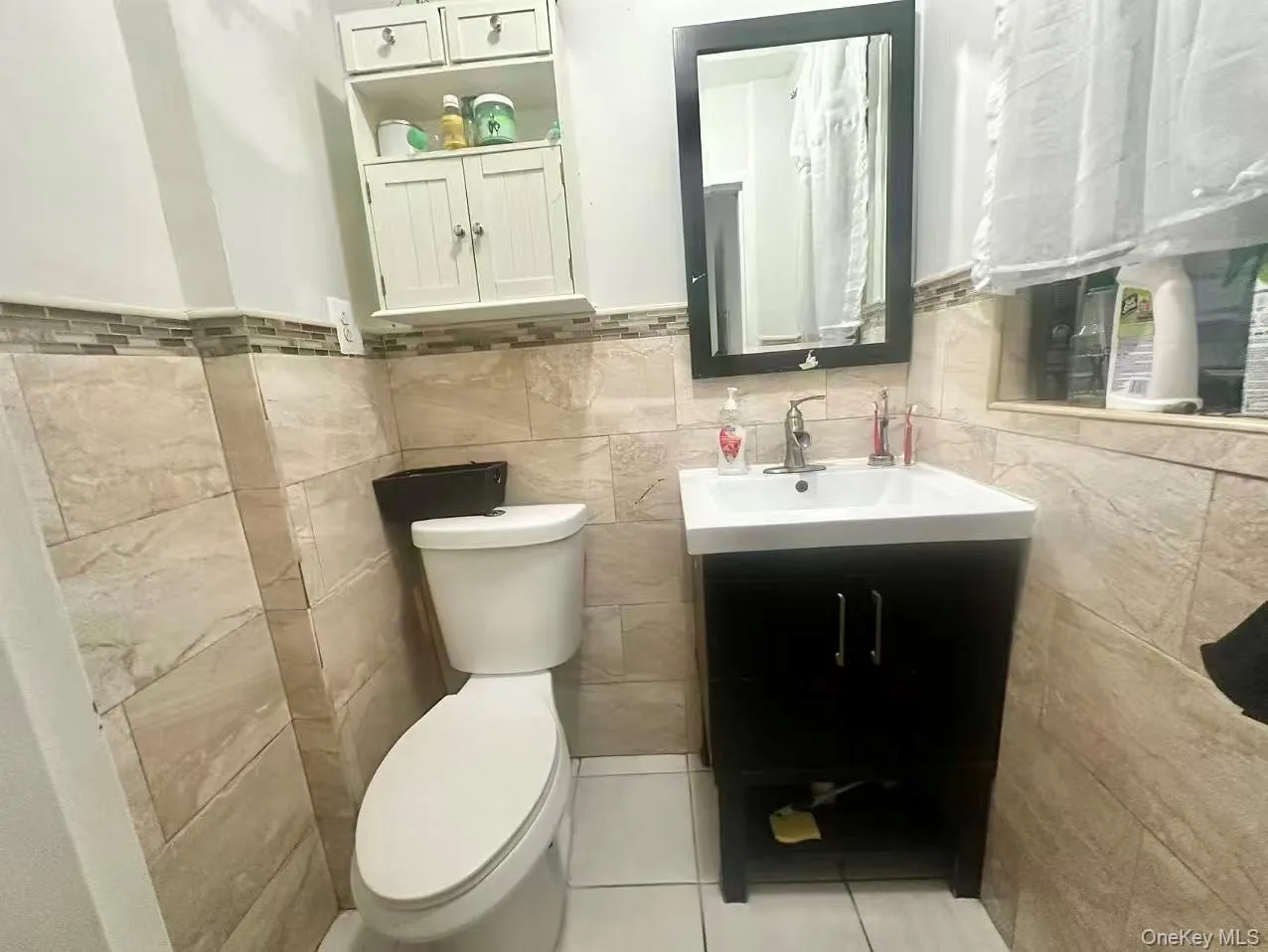 Bathroom with vanity, light tile patterned floors, tile walls, and wainscoting Bathroom with vanity, light tile patterned floors, tile walls, and wainscoting