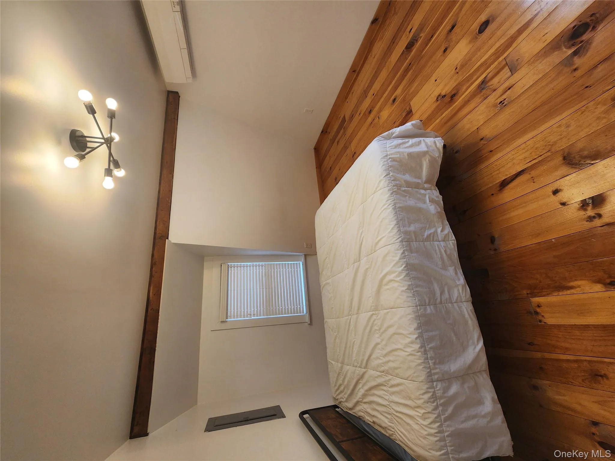 Bedroom with hardwood / wood-style floors, a chandelier, a wall mounted air conditioner, beam ceiling, and electric panel Bedroom with hardwood / wood-style floors, a chandelier, a wall mounted air conditioner, beam ceiling, and electric panel