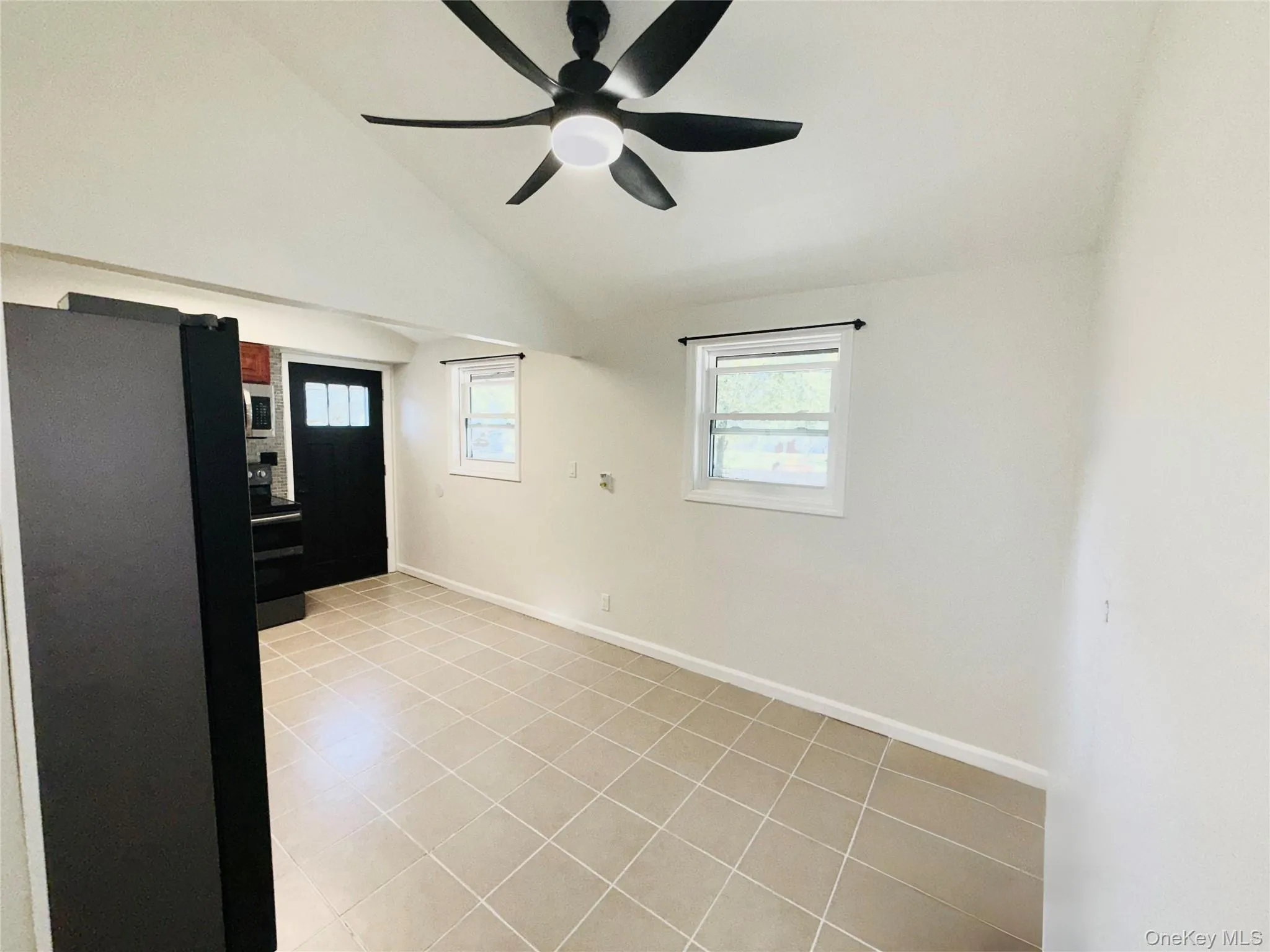 Entrance foyer with vaulted ceiling, light tile patterned floors, and a ceiling fan Entrance foyer with vaulted ceiling, light tile patterned floors, and a ceiling fan