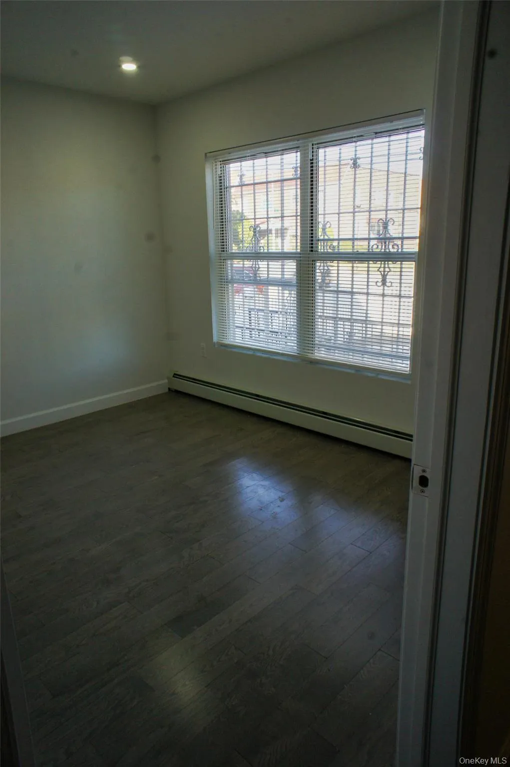 Unfurnished room with a baseboard radiator and dark wood-style floors Unfurnished room with a baseboard radiator and dark wood-style floors