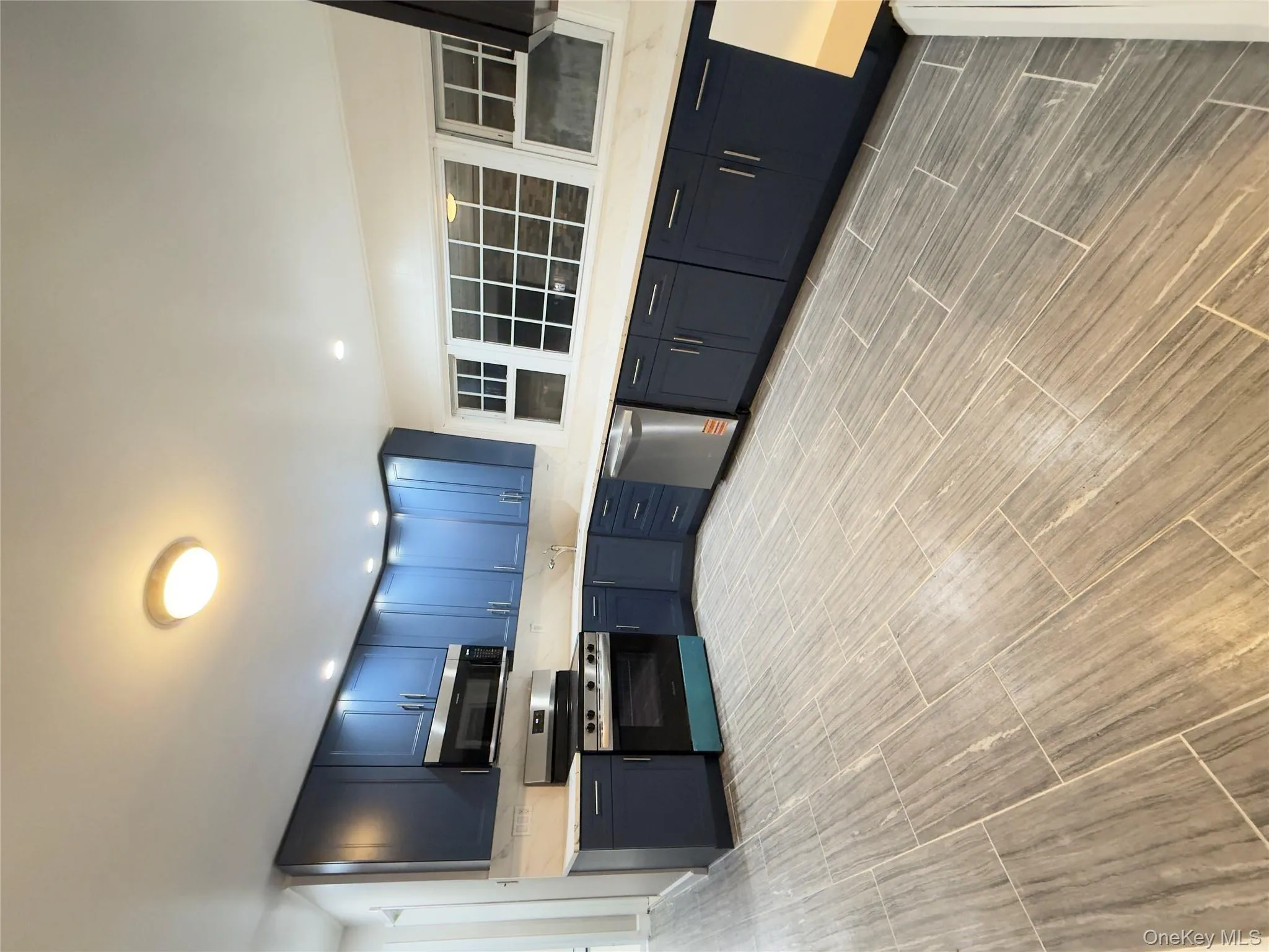 Kitchen with range, wood finish floors, stainless steel dishwasher, recessed lighting, and blue cabinets Kitchen with range, wood finish floors, stainless steel dishwasher, recessed lighting, and blue cabinets