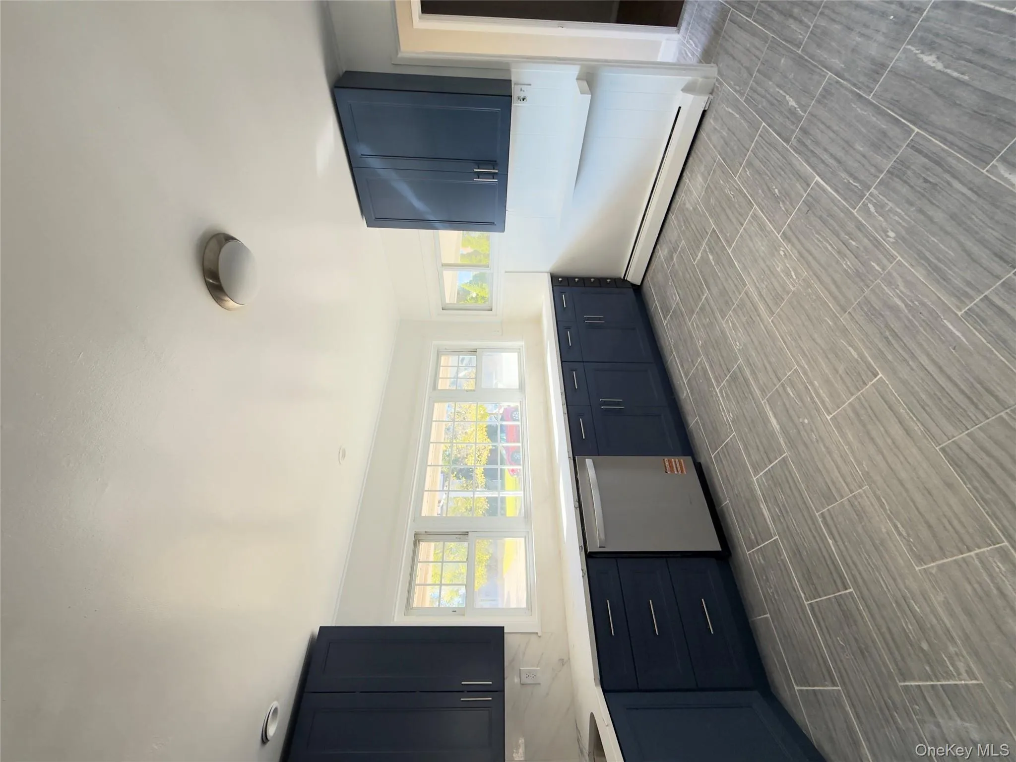 Kitchen featuring baseboard heating, blue cabinetry, healthy amount of natural light, and dishwasher Kitchen featuring baseboard heating, blue cabinetry, healthy amount of natural light, and dishwasher