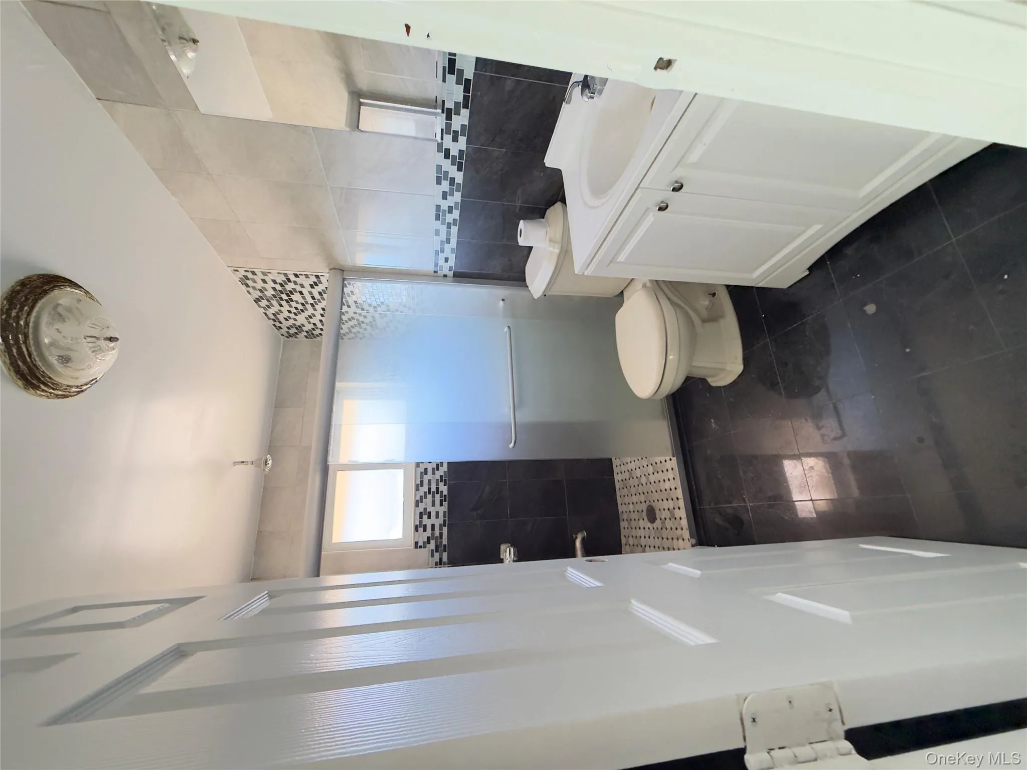 Bathroom featuring tile walls, vanity, a stall shower, and dark tile patterned flooring Bathroom featuring tile walls, vanity, a stall shower, and dark tile patterned flooring